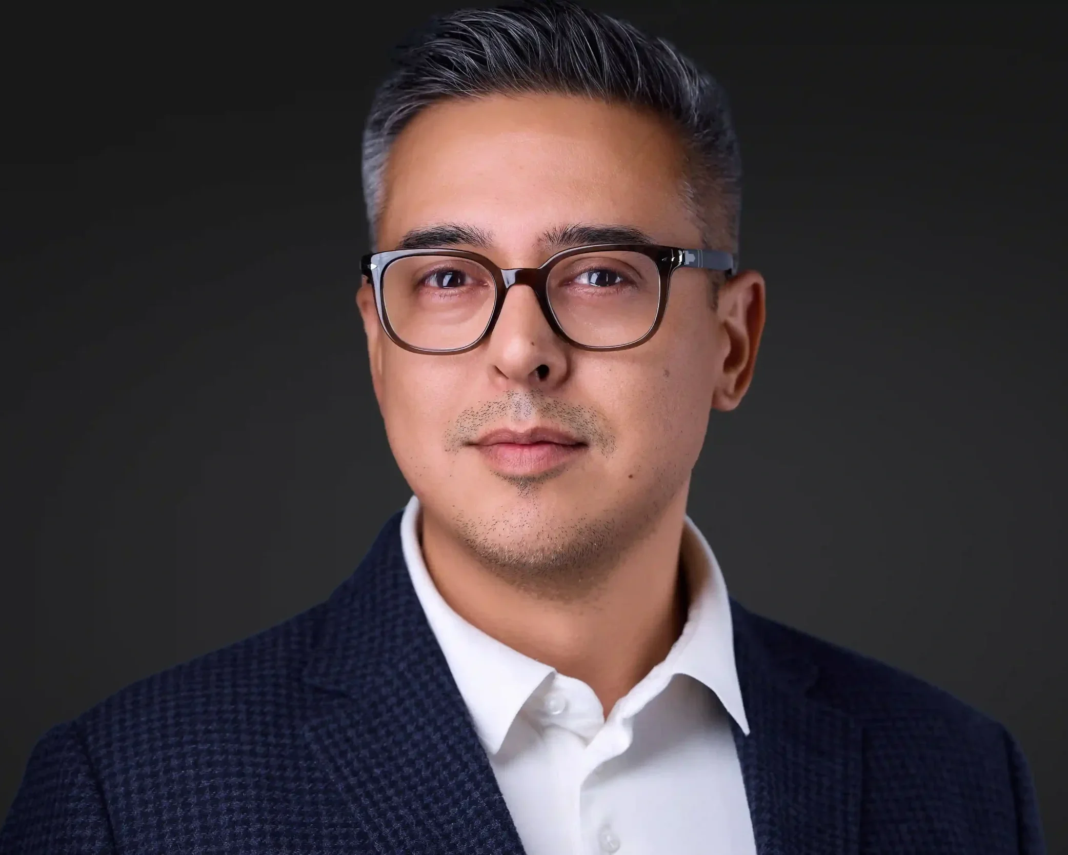 Professional headshot of a man in a suit against  a dark background, Las Vegas corporate headshot photographer  Pandorica Headshot Studio