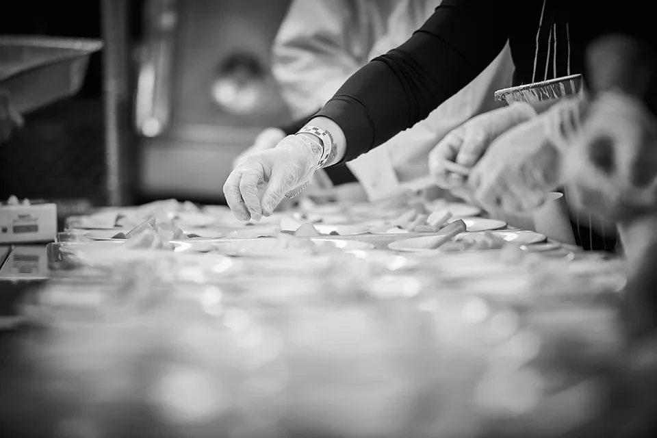 People working together on a project, wearing gloves, organizing or preparing items on a table in a professional setting.