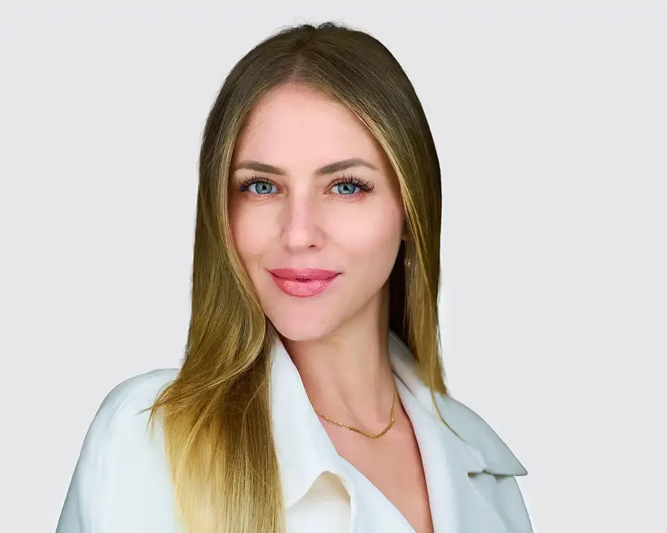 Professional headshot of a woman with long blonde hair wearing a white blazer against a light gray background, photographed at Pandorica Headshot Studio in Las Vegas