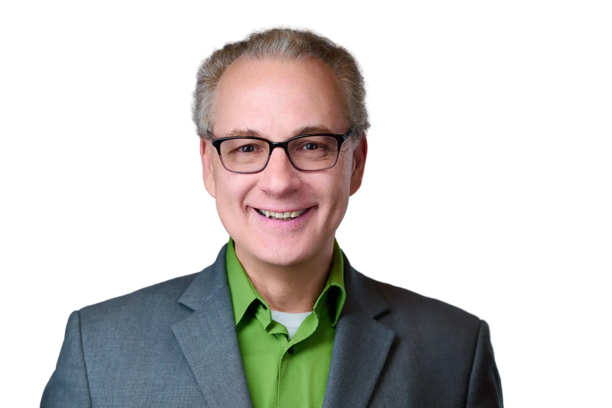 Smiling man with glasses, wearing a grey suit and green shirt, posing against a white background.