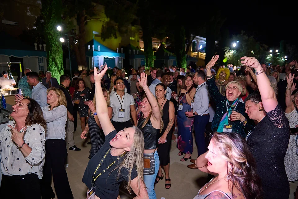 Group of people at a lively party or celebration, dancing and enjoying themselves indoors at night.