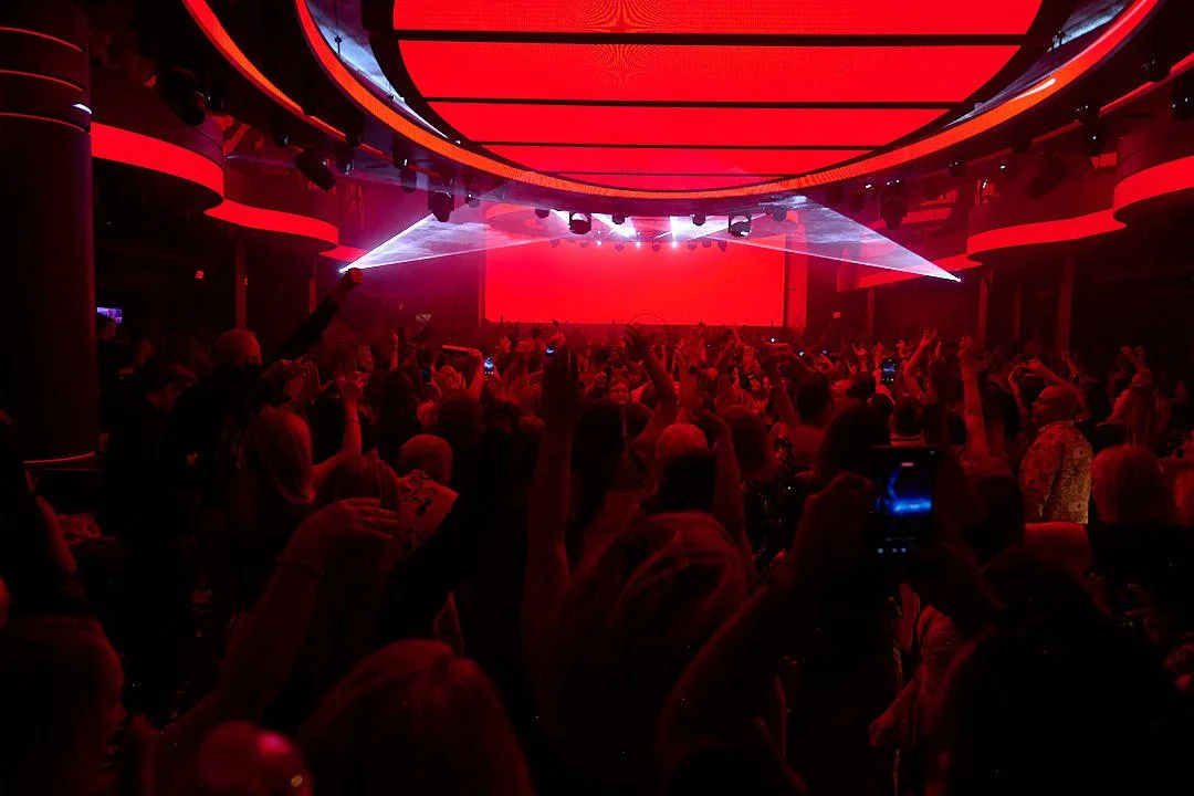 Crowd at a nightclub or concert with red lighting and laser effects
