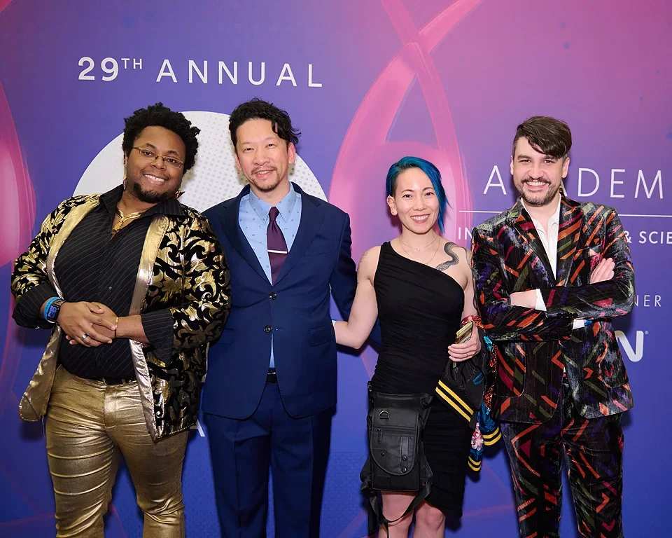 Four individuals standing together at the 29th Annual event, in front of a purple backdrop with the event's logo and text.