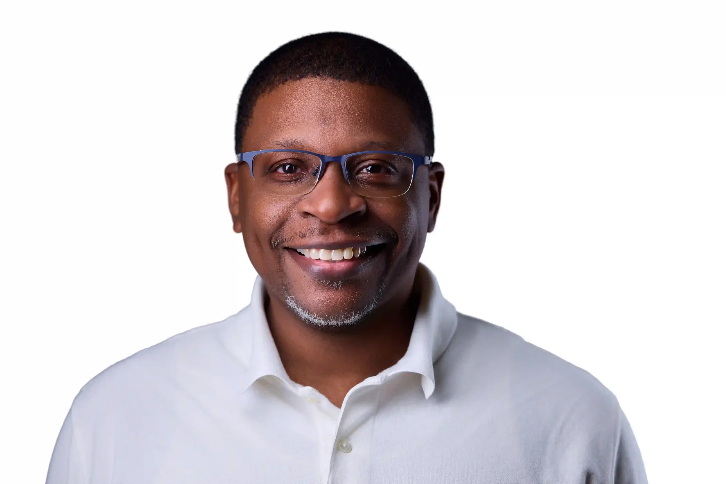 A smiling man wearing glasses and a white collared shirt against a plain white background.