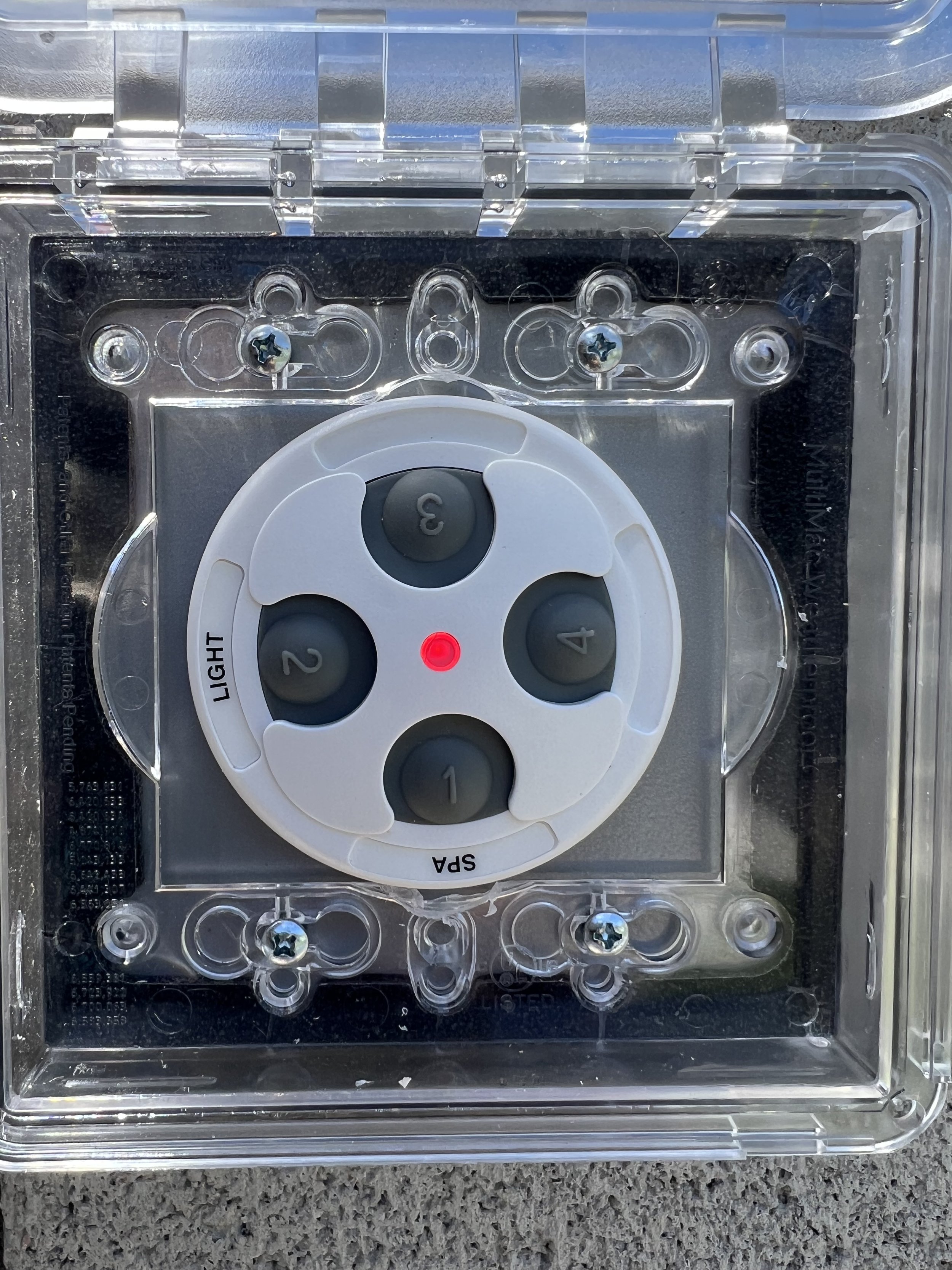 Outdoor pool or spa controller with four buttons labeled 1 to 4, enclosed in a clear protective case. Features "Light" and "Spa" labels and a red indicator light.
