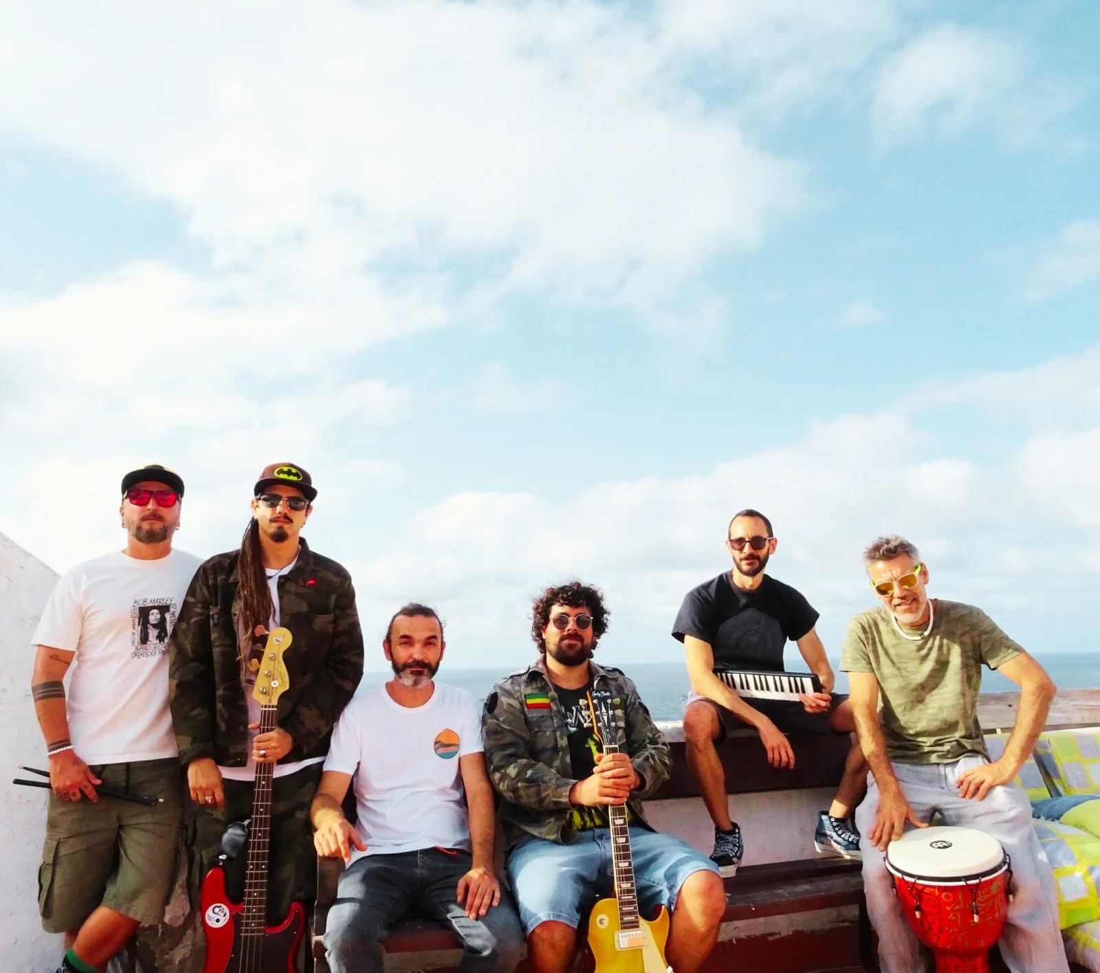 Siete hombres con instrumentos musicales en un espacio exterior con cielo y nubes.