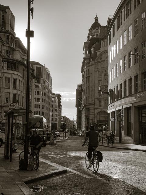 Street scene with cyclists, pedestrians, and old buildings in black and white