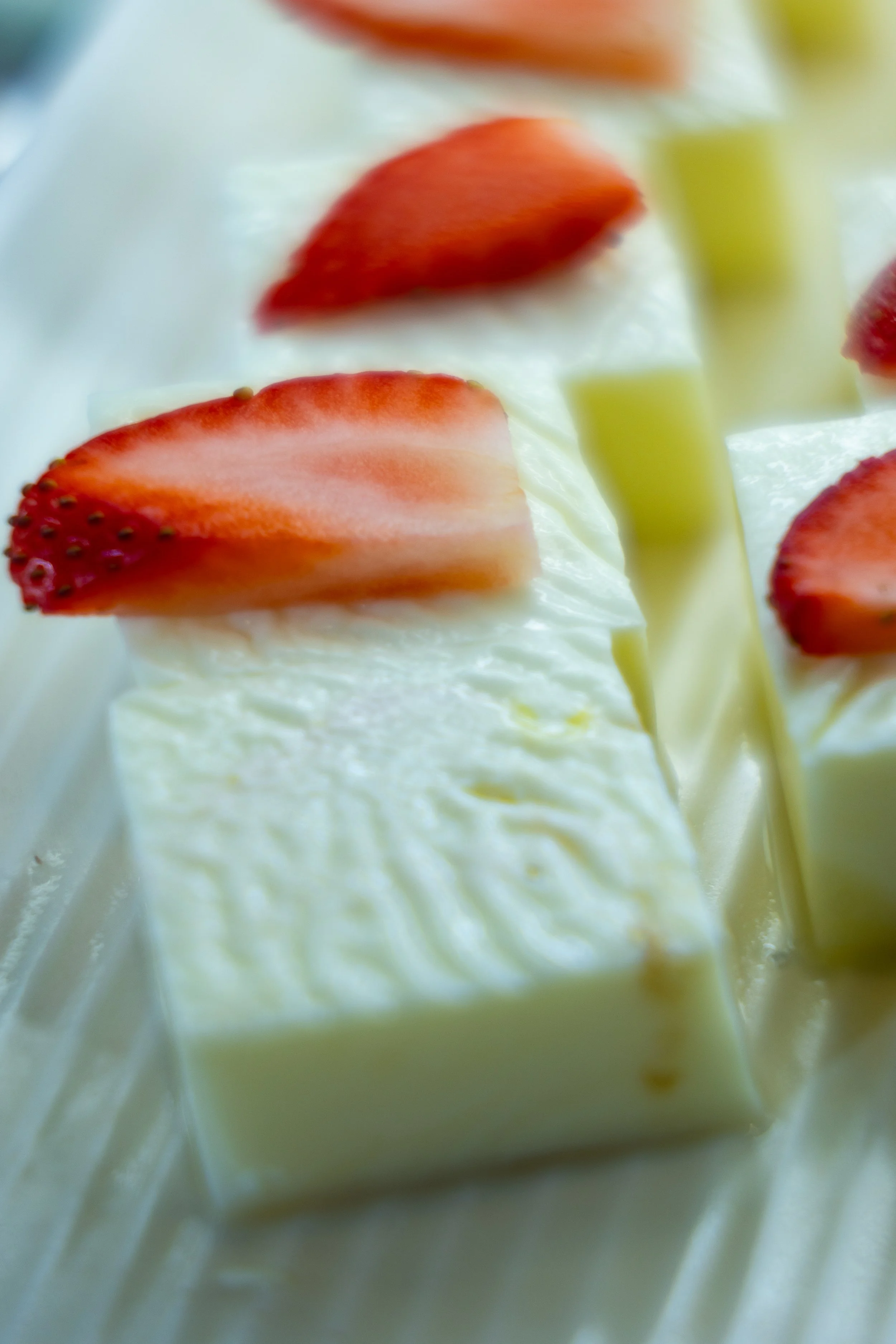 Close-up of a white chocolate or vanilla mousse dessert topped with fresh strawberry slices.