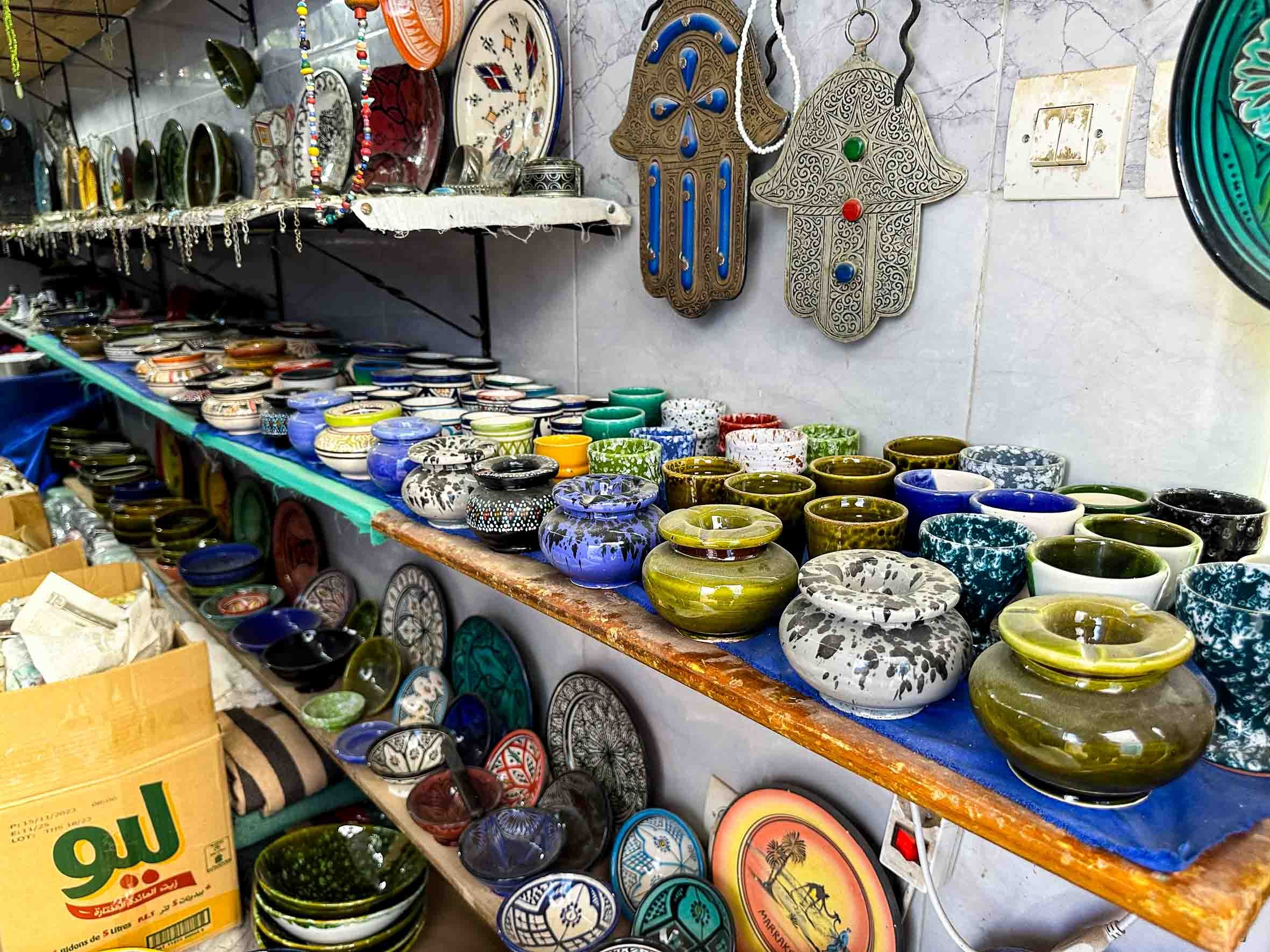 Colorful ceramic bowls and decorative wall hangings displayed on shelves at a marketplace.