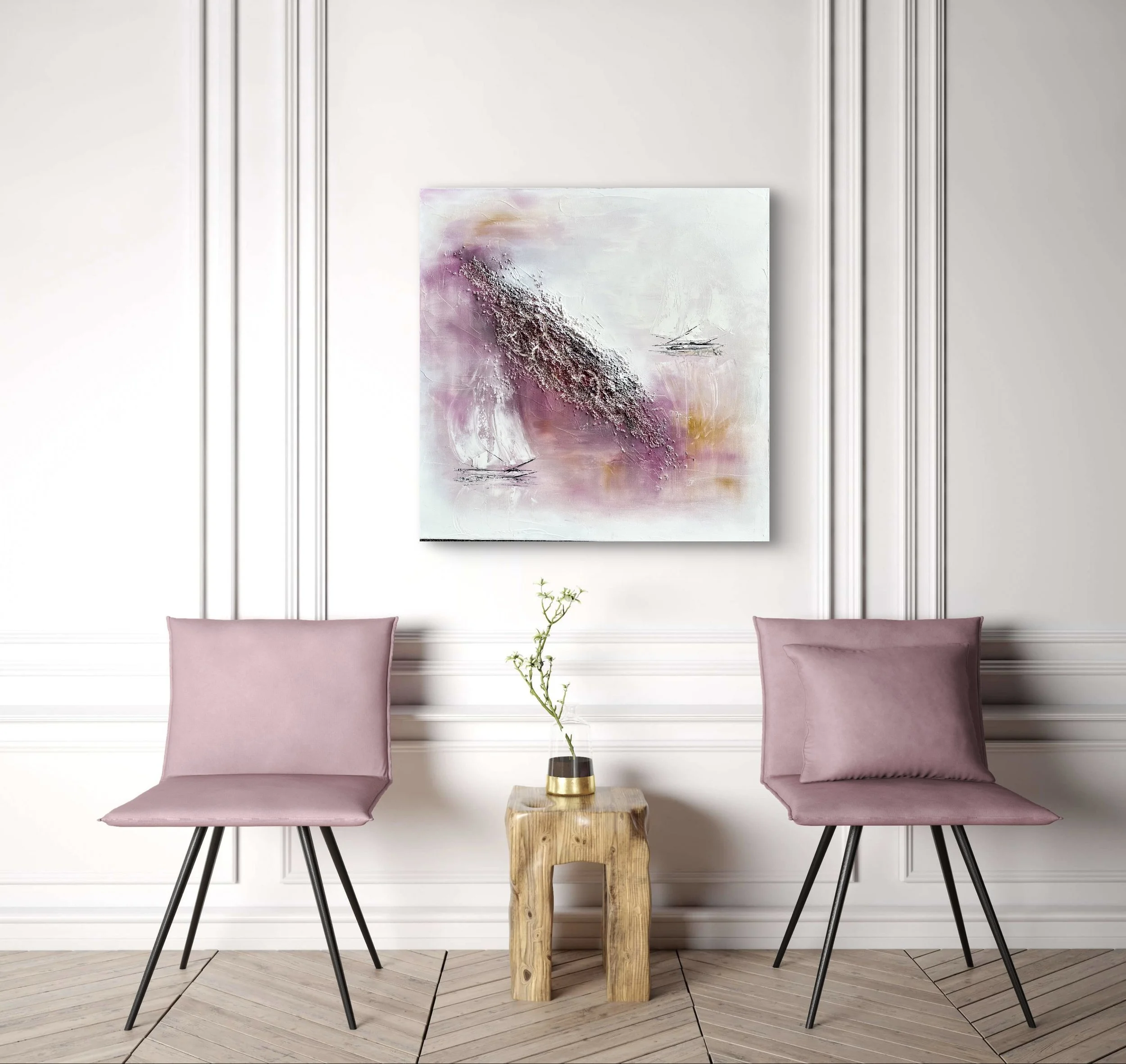 Modern interior with two pink chairs, a small wooden table with a plant in a gold-accented pot, and an abstract painting with pink and white tones on a white wall with decorative molding.
