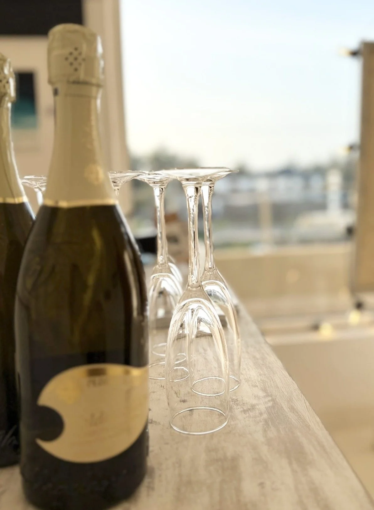 Three overturned champagne glasses and a bottle of champagne on a wooden table.