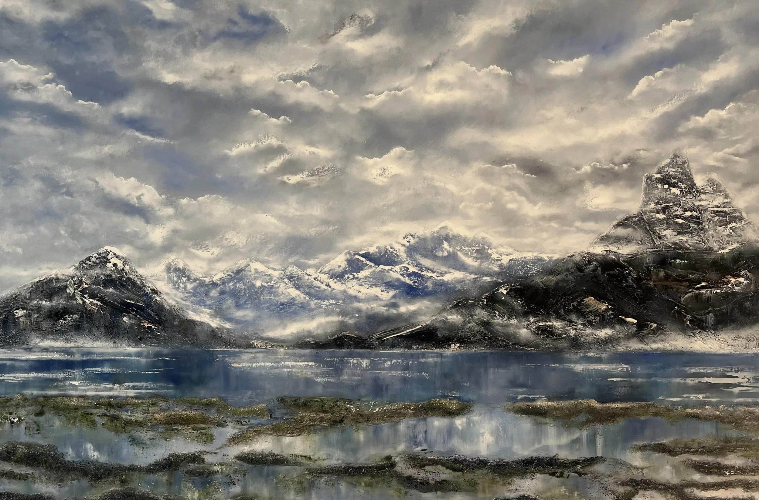 Snow-capped mountains reflected in a calm lake with overcast sky.