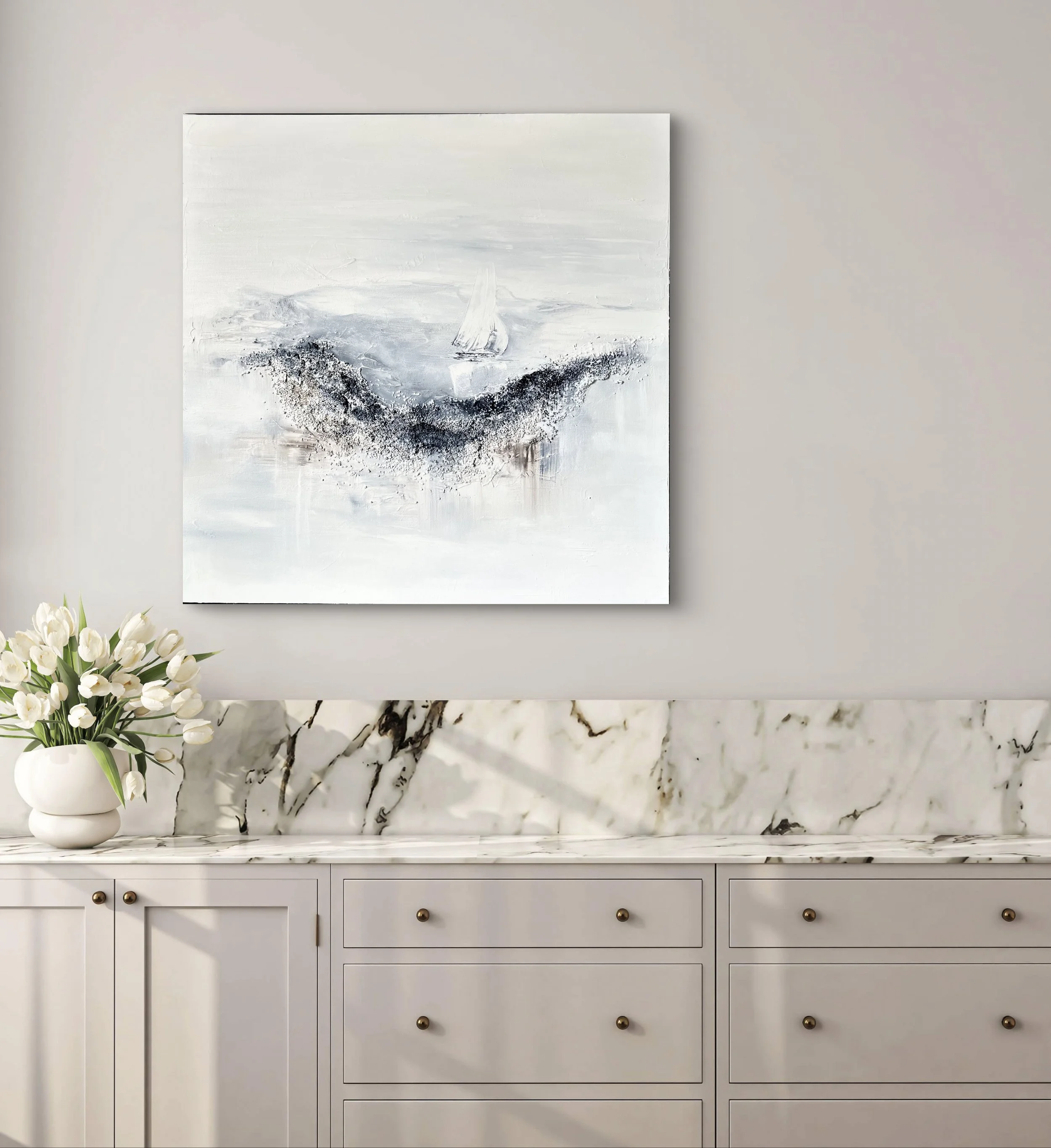 A white marble sideboard with gold knobs, a marble backsplash, a vase with white tulips, and abstract sea-themed artwork on a beige wall.