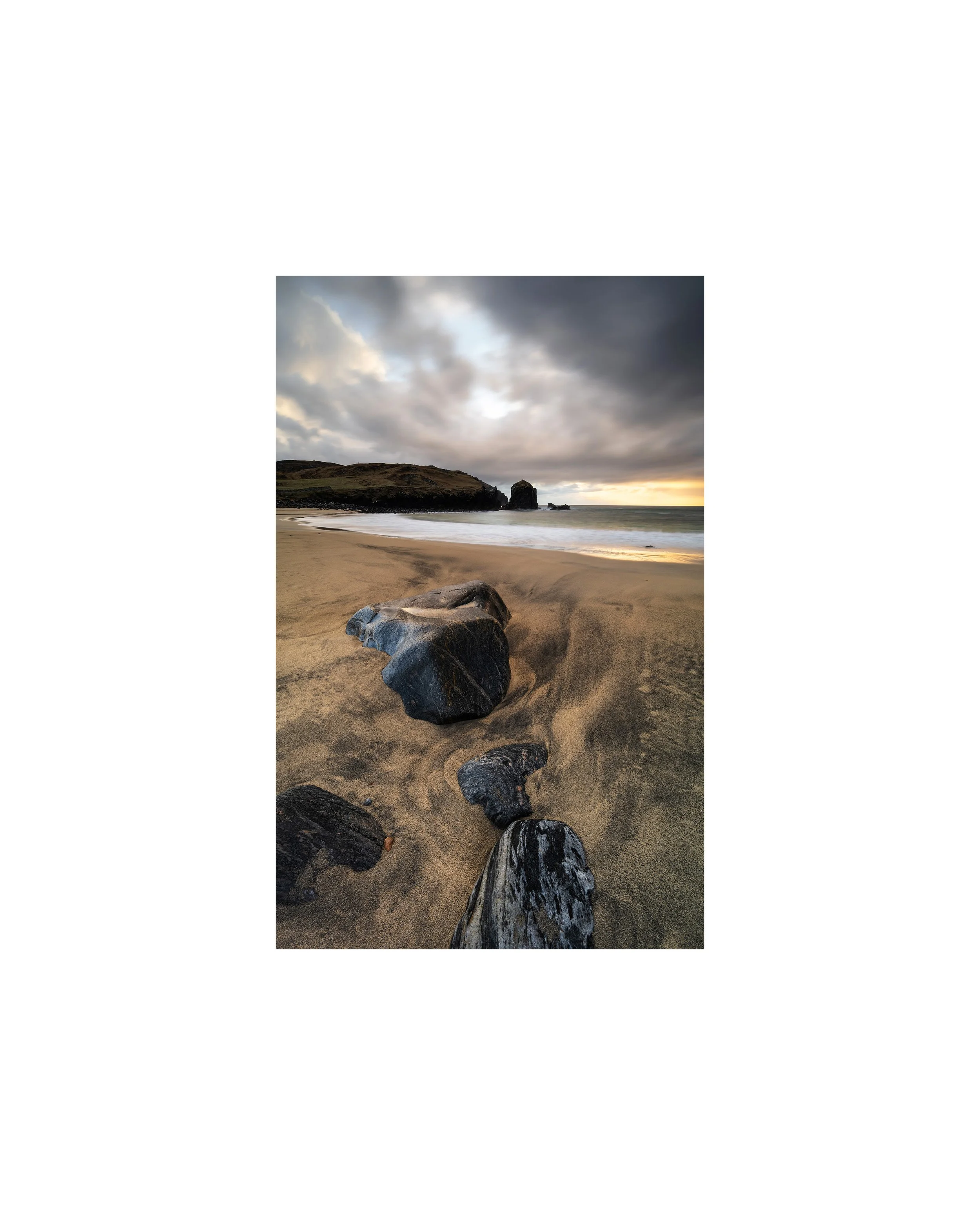 Dalbeg Beach photography print, isle of Lewis showing warm evening light breaking through cloud and running across wet sand, with carved tide patterns and dark rocks on the Isle of Lewis.