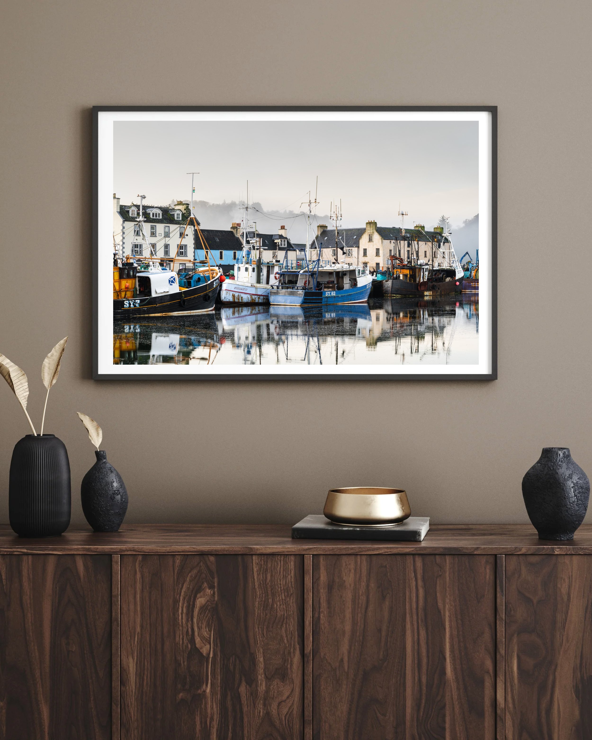 Framed Stornoway Harbour photography print hanging on an interior wall, showing fishing boats, calm water and soft winter mist.