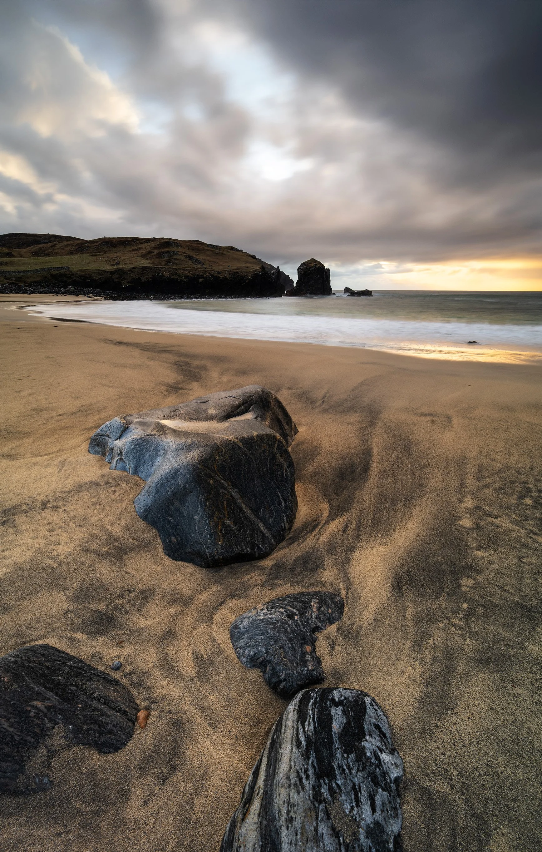 Dalbeg Beach at sunset with warm light on the cliffs and soft Atlantic waves running across the sand on the Isle of Lewis.
