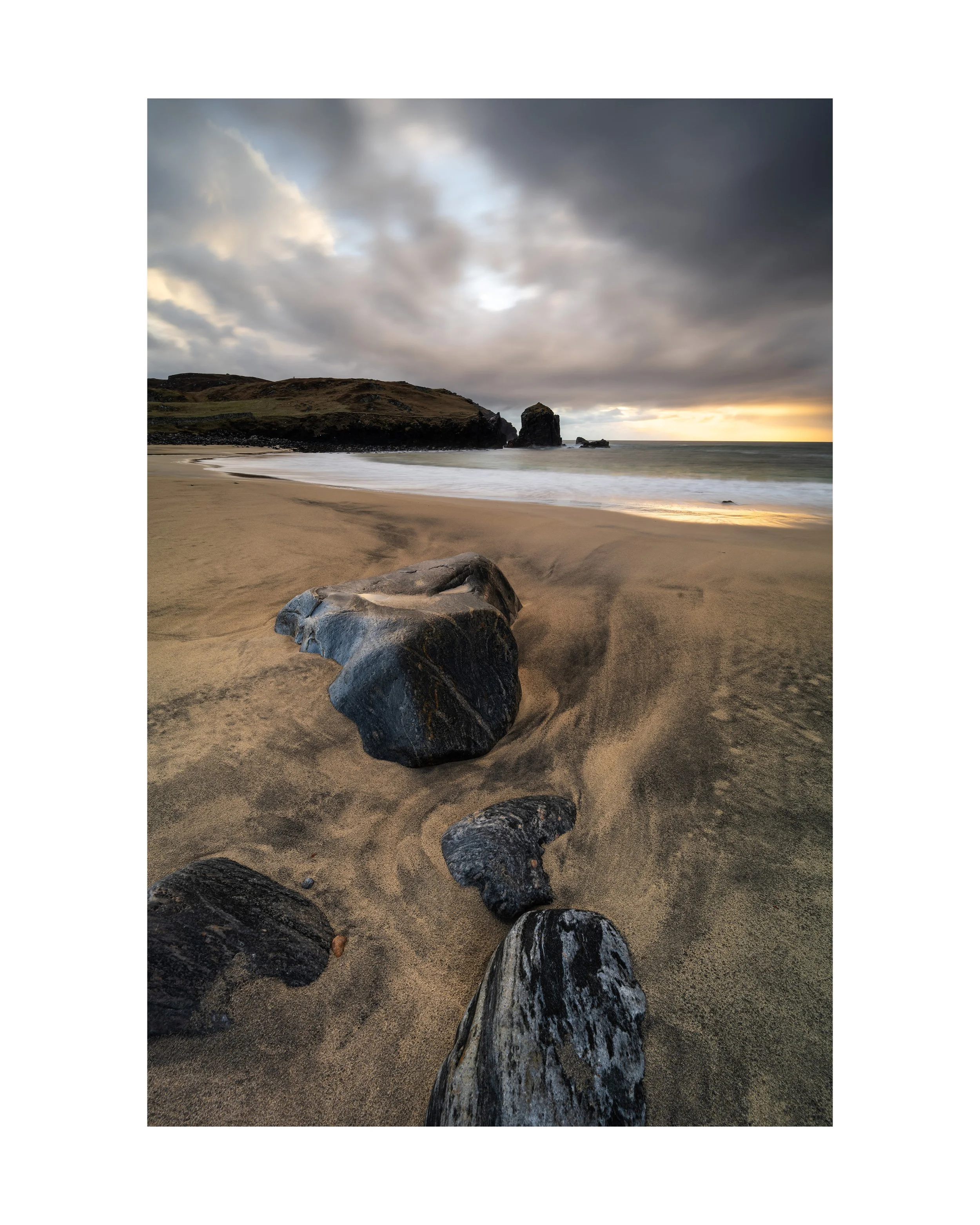 Dalbeg Beach photography print, isle of Lewis showing warm evening light breaking through cloud and running across wet sand, with carved tide patterns and dark rocks on the Isle of Lewis.