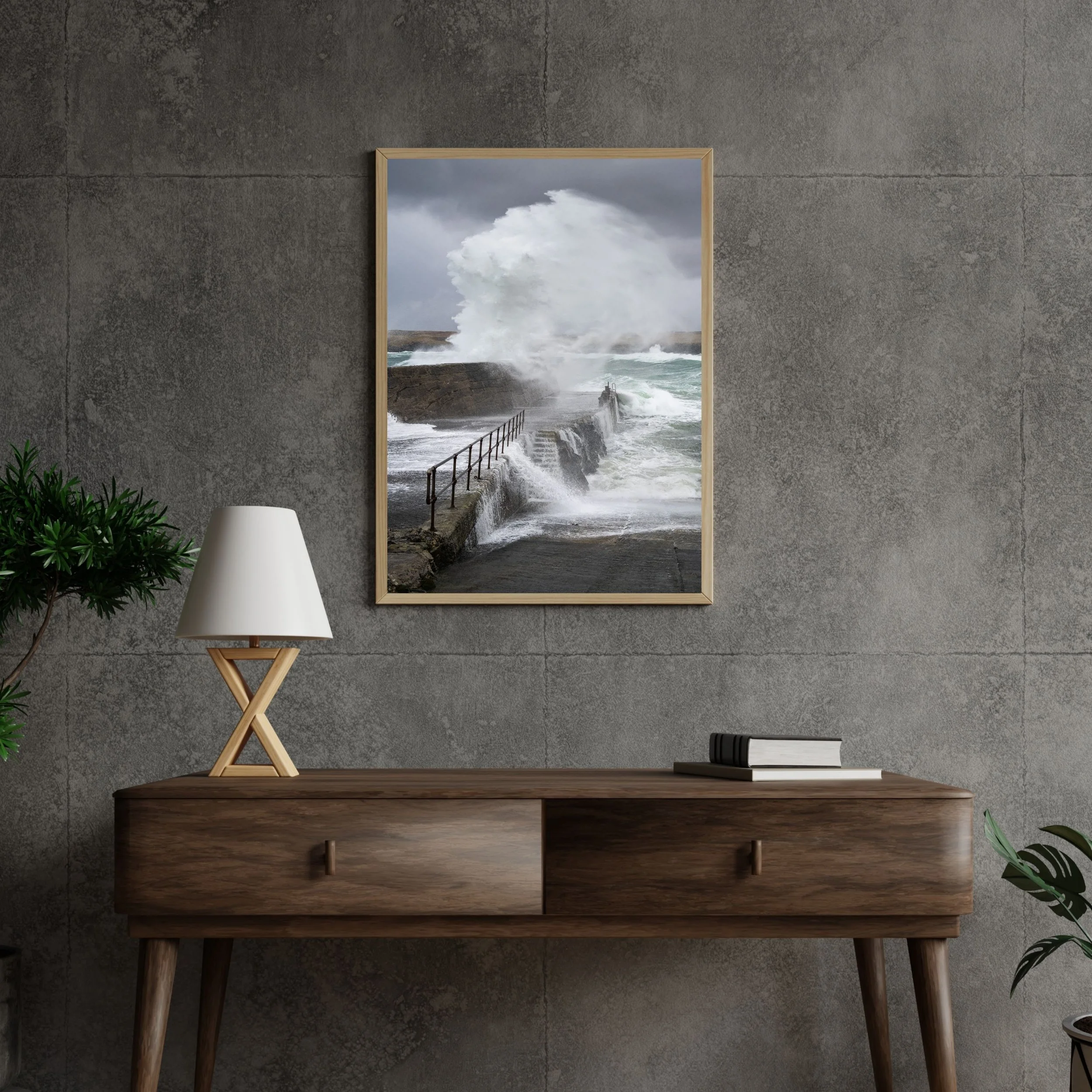 Framed fine‑art print showing an Atlantic storm wave hitting the harbour wall at Port of Ness, hung on a wall.