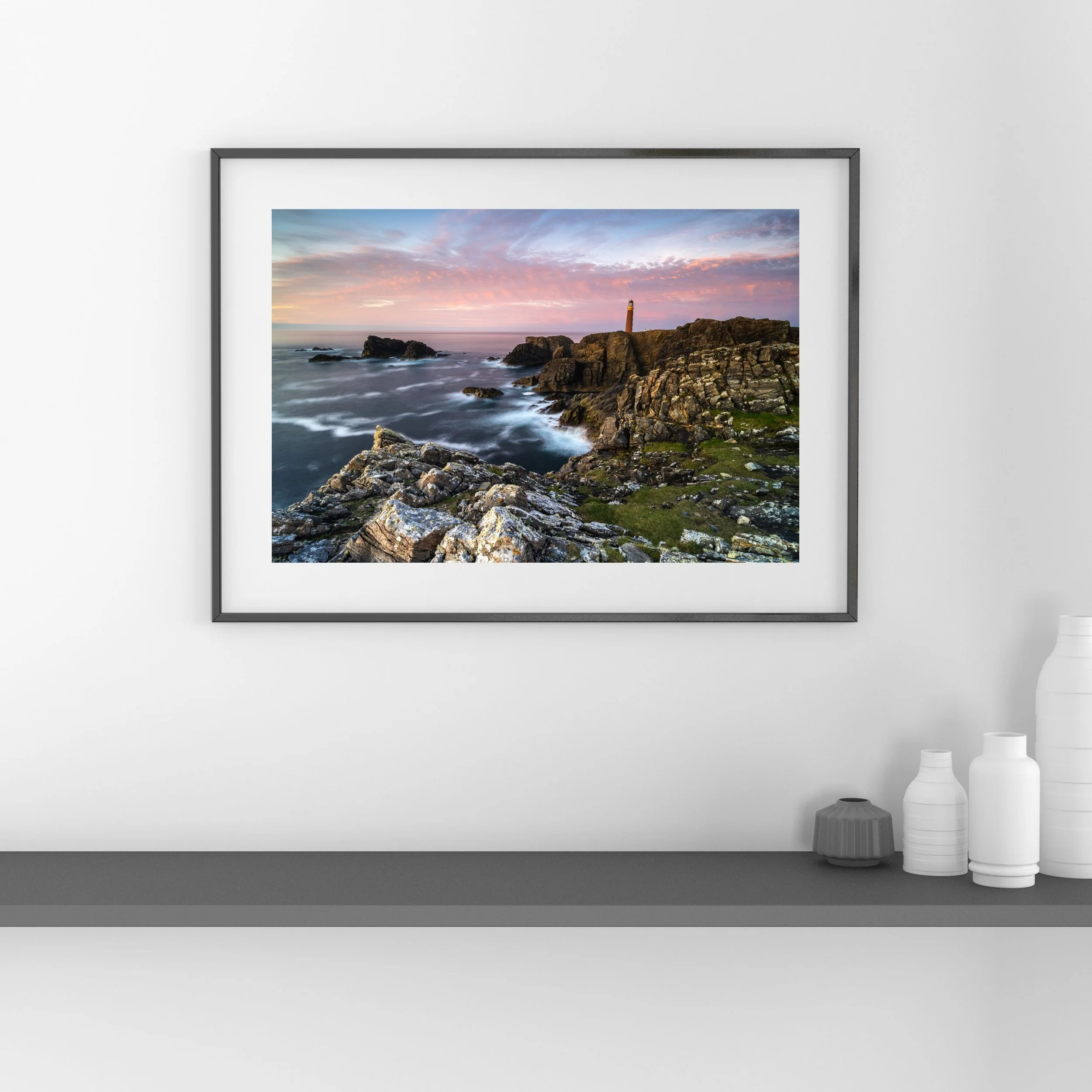 Framed print of the Butt of Lewis Lighthouse at pink sunset, displayed on a wall.