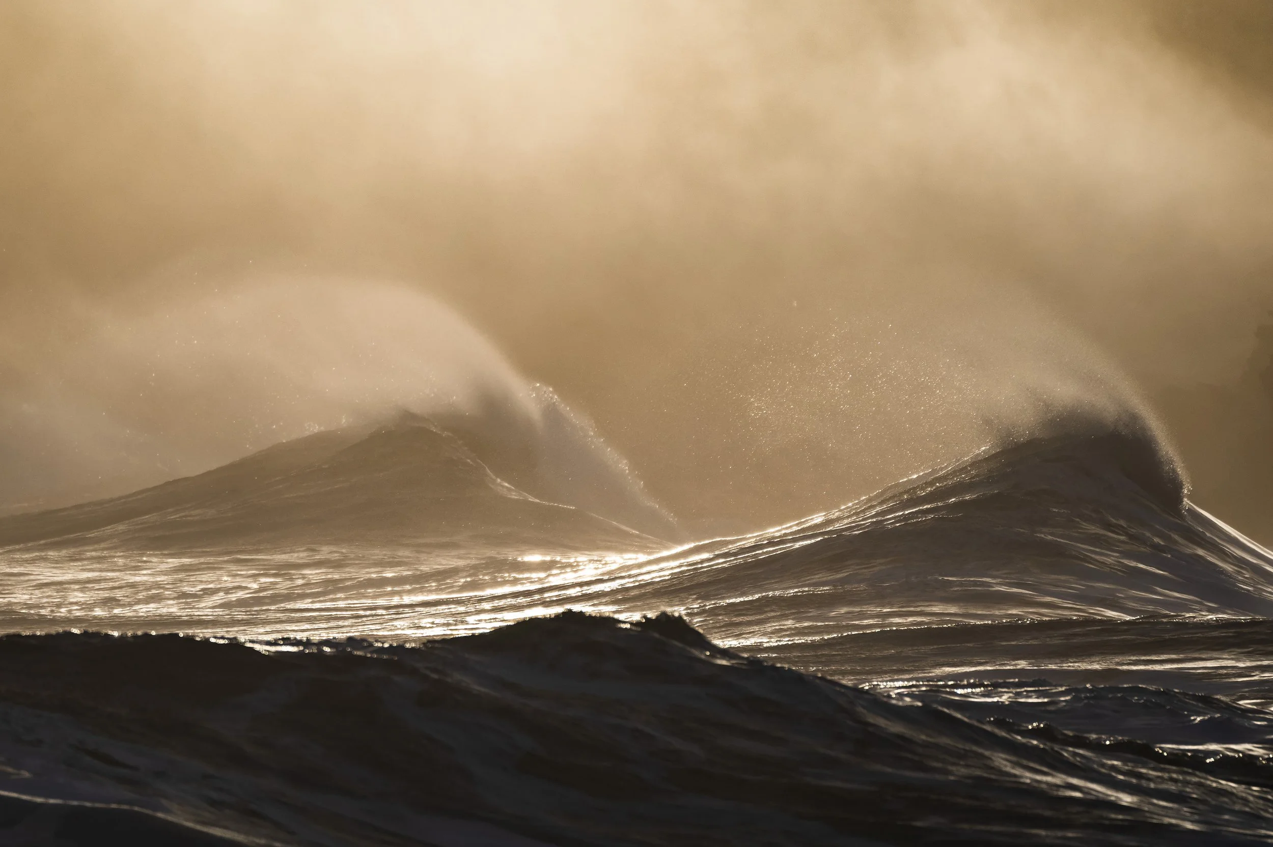 Storm waves rolling into the harbour at Port of Ness, with golden sea spray catching the light during a winter Atlantic swell.
