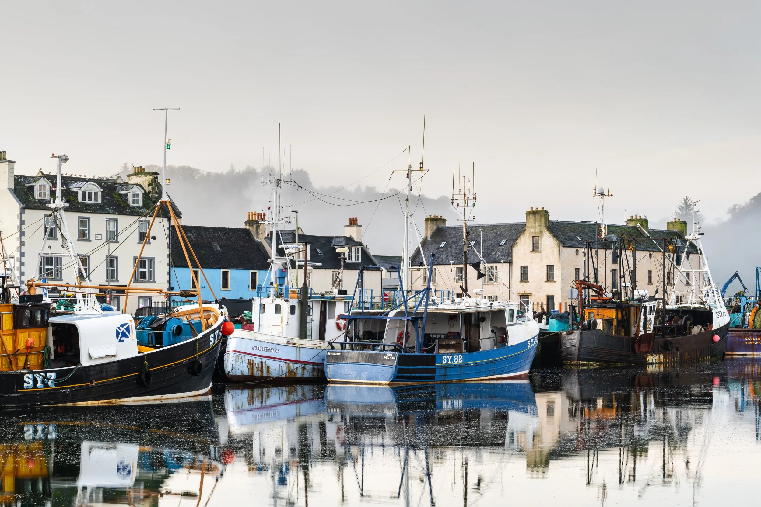 Stornoway Harbour photography print showing fishing boats in calm winter light, with soft mist and reflections across the still water.