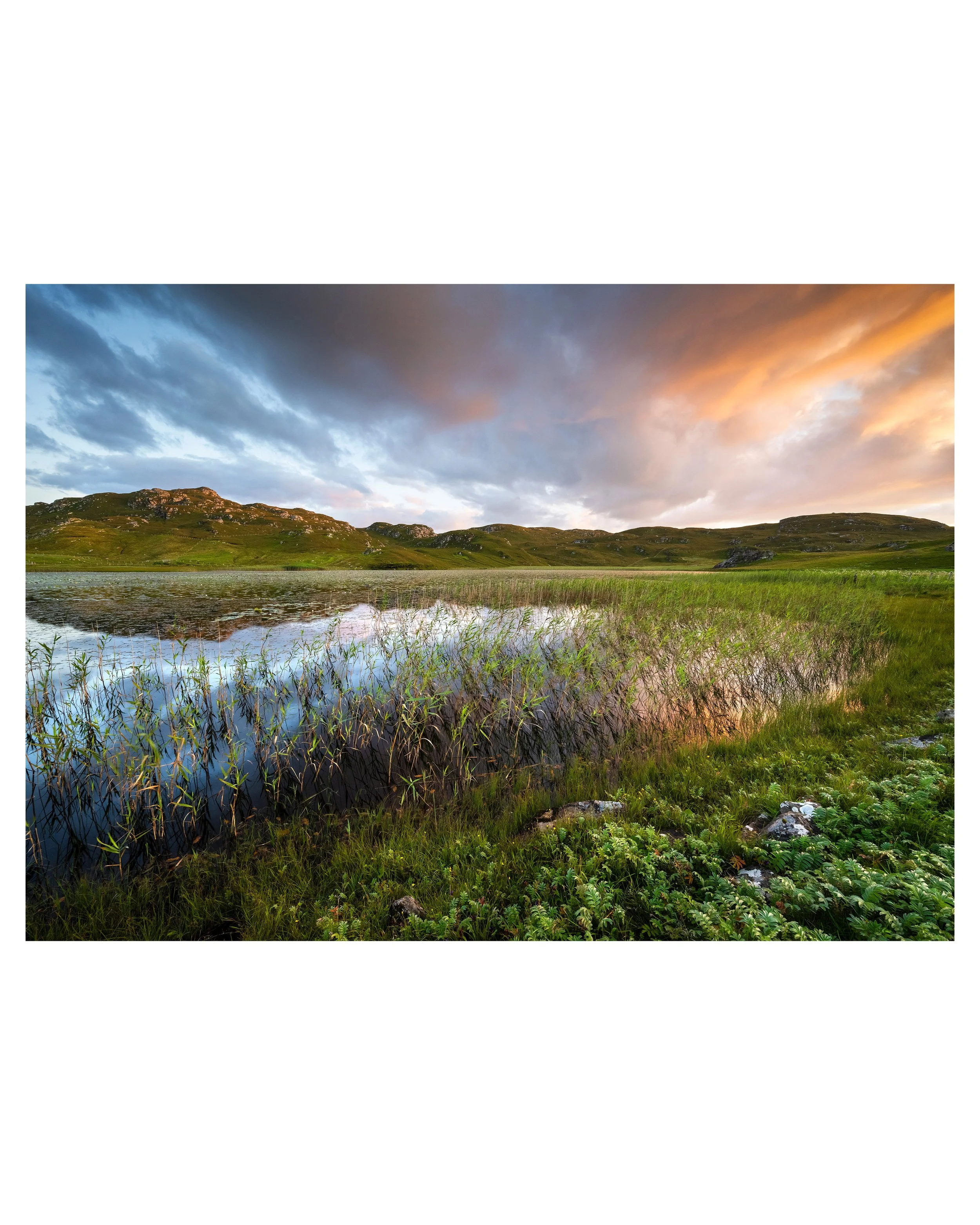 Sunset over Dalbeg Loch on the Isle of Lewis, with pink and orange tones in the sky mirrored on the calm surface.