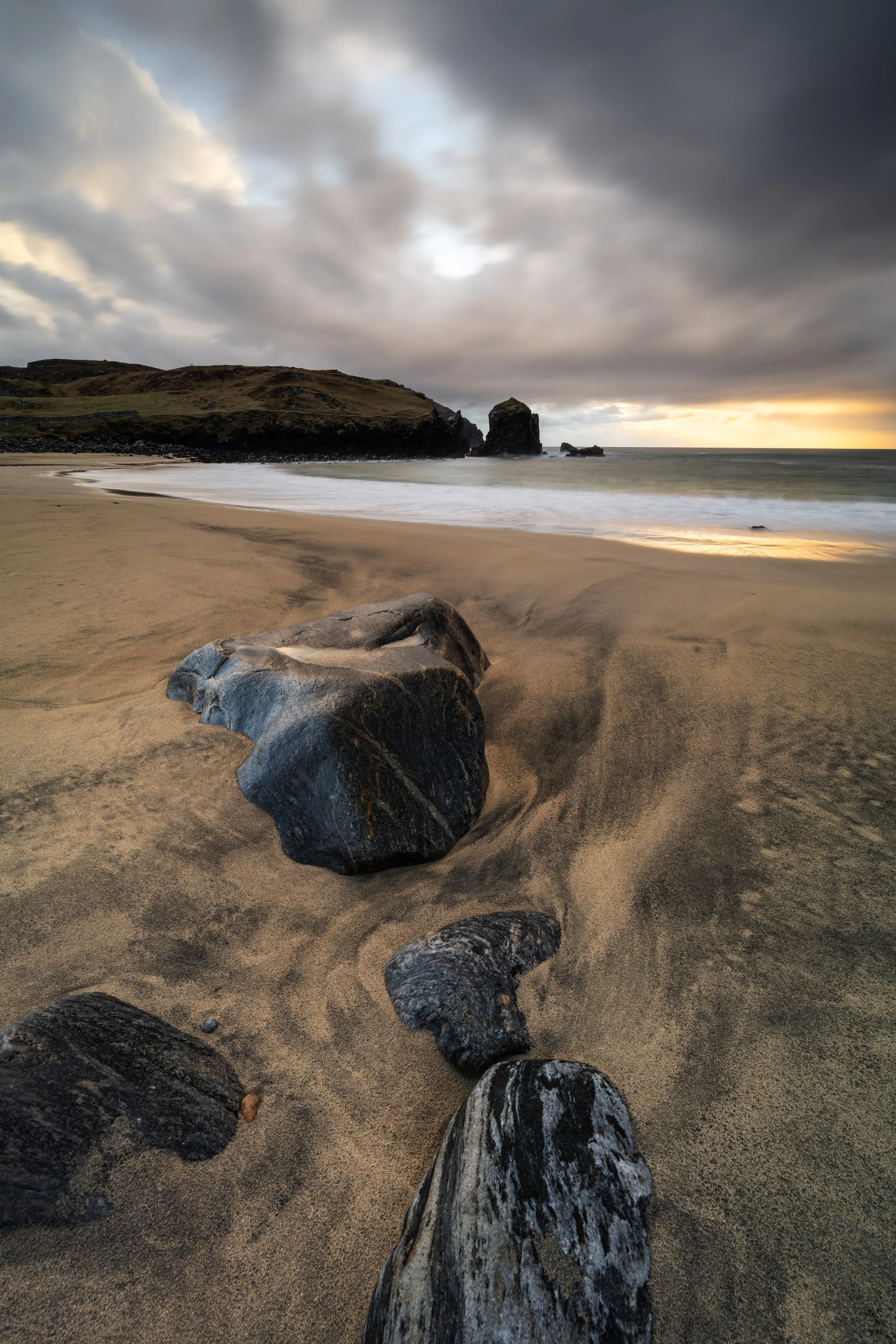 Dalbeg Beach on the Isle of Lewis with warm evening light running across wet sand, carved tide patterns, and high cliffs framing the bay, from the fine art print “Dalbeg Beacht