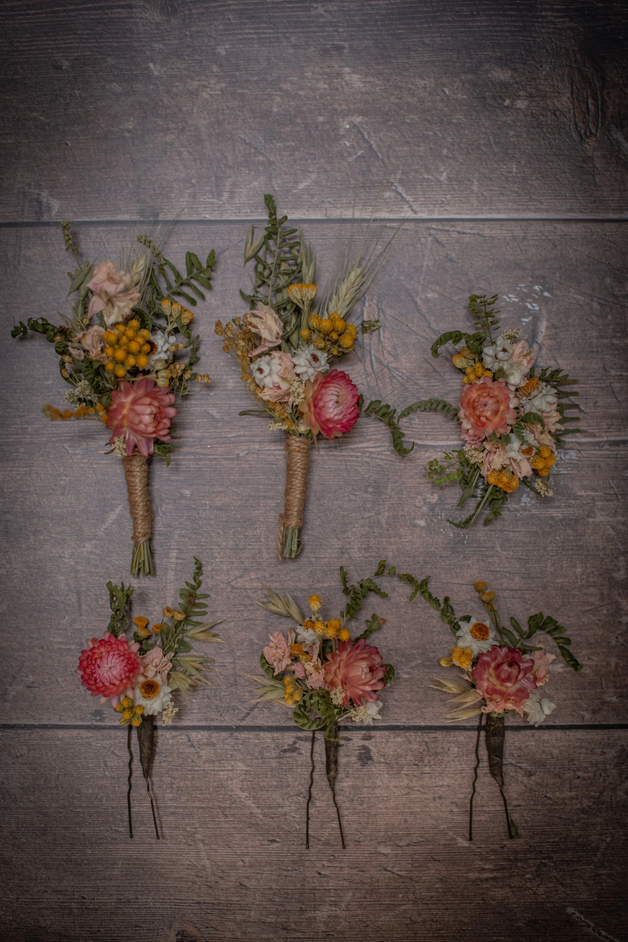 A pretty set of dried flower wedding accessories - buttonholes / buttonieres, a hair comb and hair pins. All in a palette of soft pins, whites and yellow, with green ferns. A very natural, country  / wild flower look.
