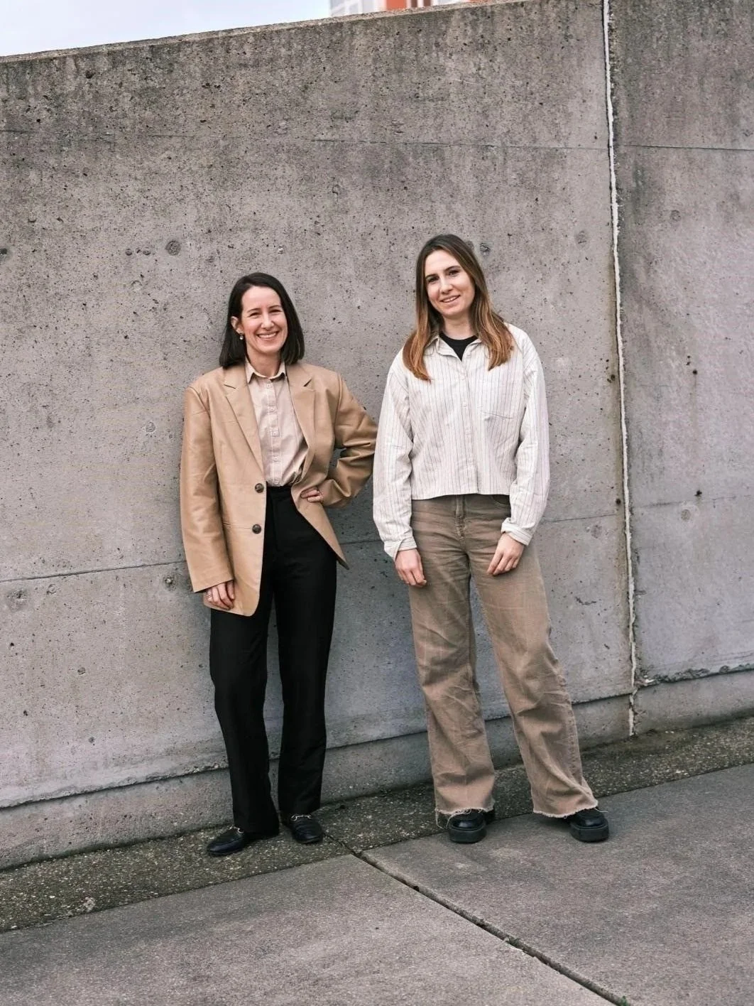 The founders of Nomet, Mona and An-Sofie, standing in front of a wall