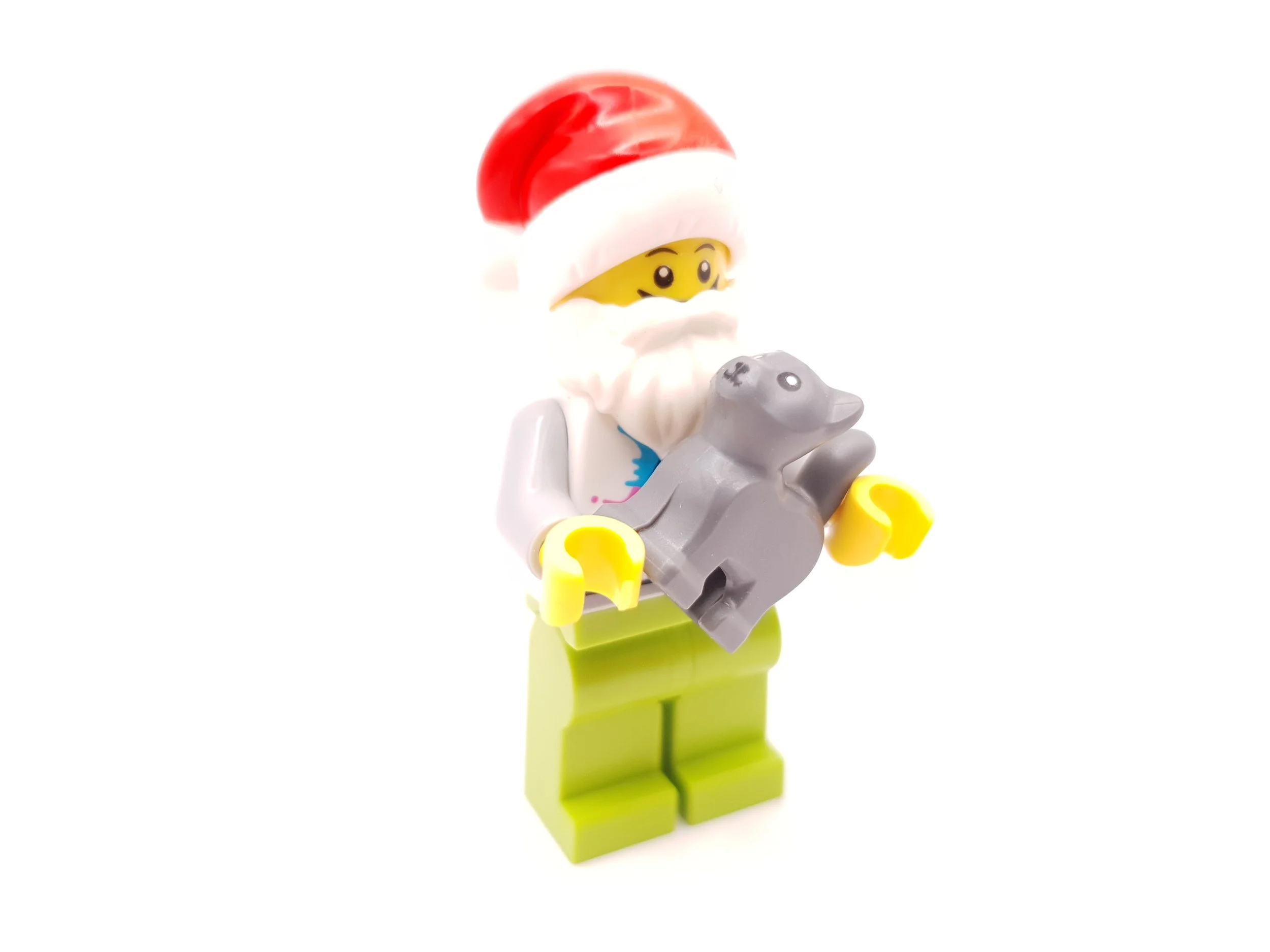 LEGO Santa Claus minifigure holding a gray dog, with a white beard, yellow face, red and white Santa hat, yellow hands, and lime green legs.