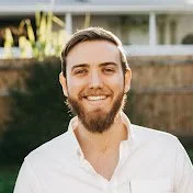 Luke Wiles youtube logo A smiling young man with a beard wearing a white shirt outdoors.
