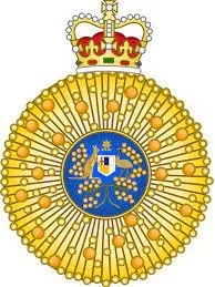 A golden medal with a blue emblem in the center featuring a crown and shield, topped with a royal crown.