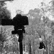 Matt M youtube logo A person walking outdoors among trees, possibly near a camera mounted on a tall pole or structure.