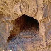 QLD Queensland Abandoned Mines youtube logo A small cave entrance in a rocky landscape.