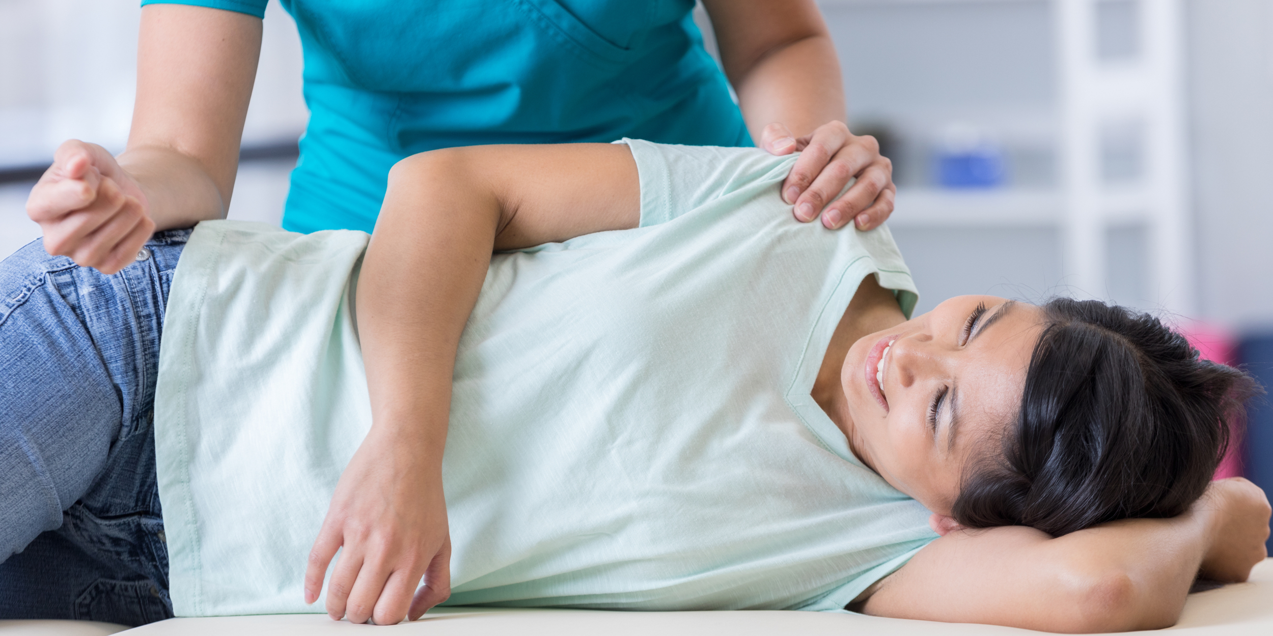 Image of a chiropractor adjusting a smiling patient on the table.