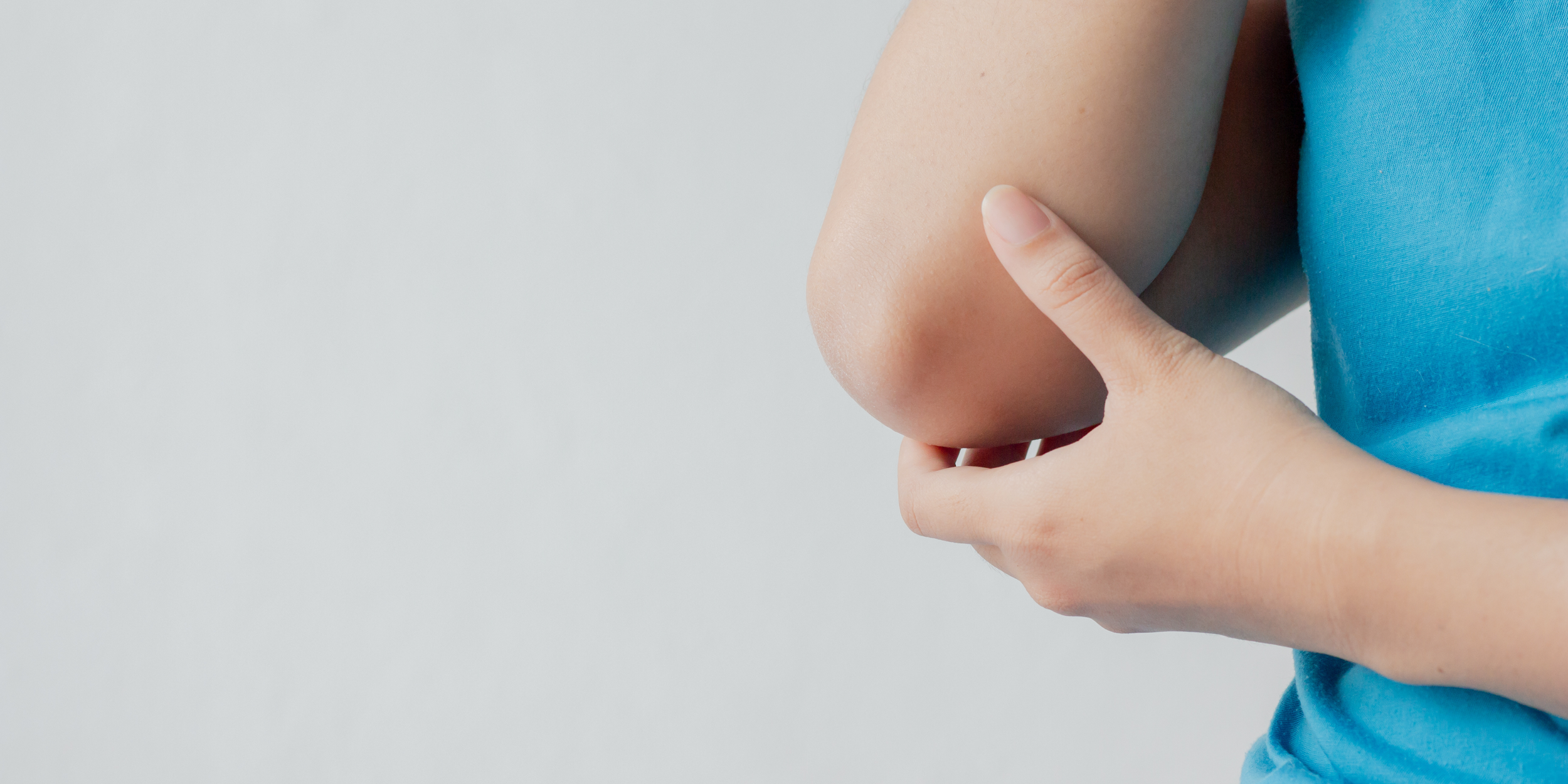 Closeup image of a woman's elbow being held by her other hand, as if she's hurt it.