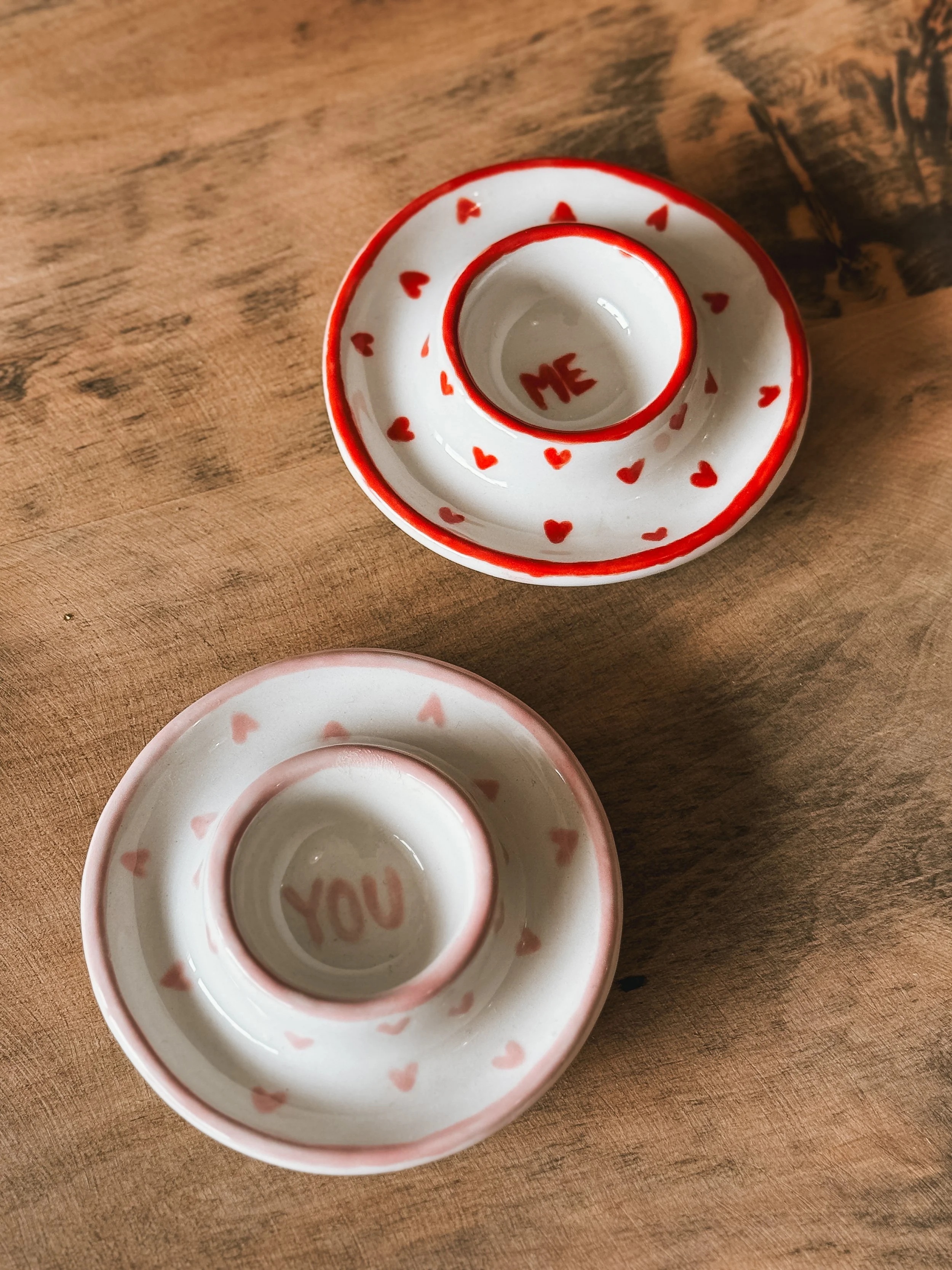 Duo de coquetiers illustrés dans des teintes rose et rouge.