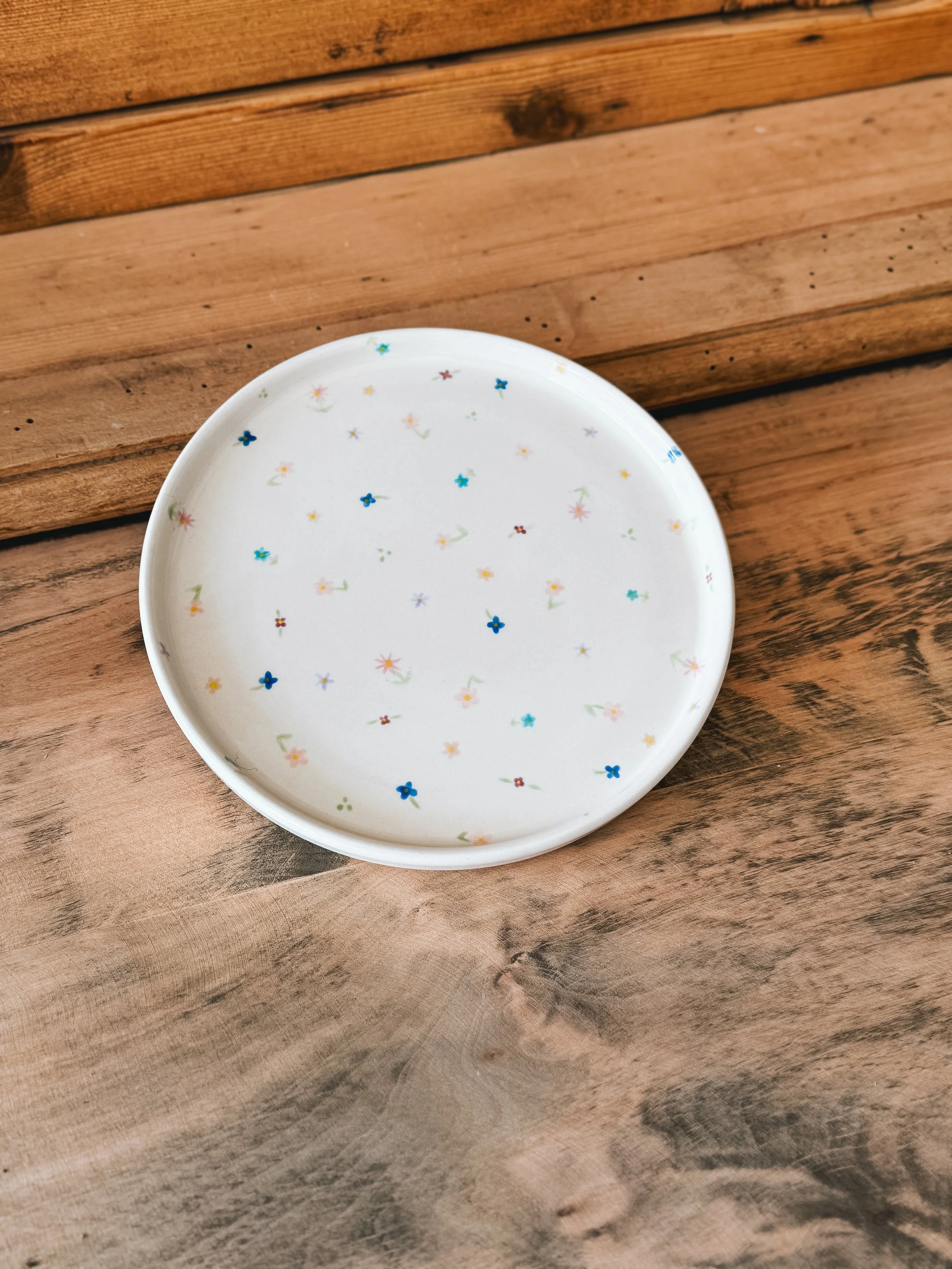 Petite assiette illustrées avec des fleurs de plusieurs couleurs.