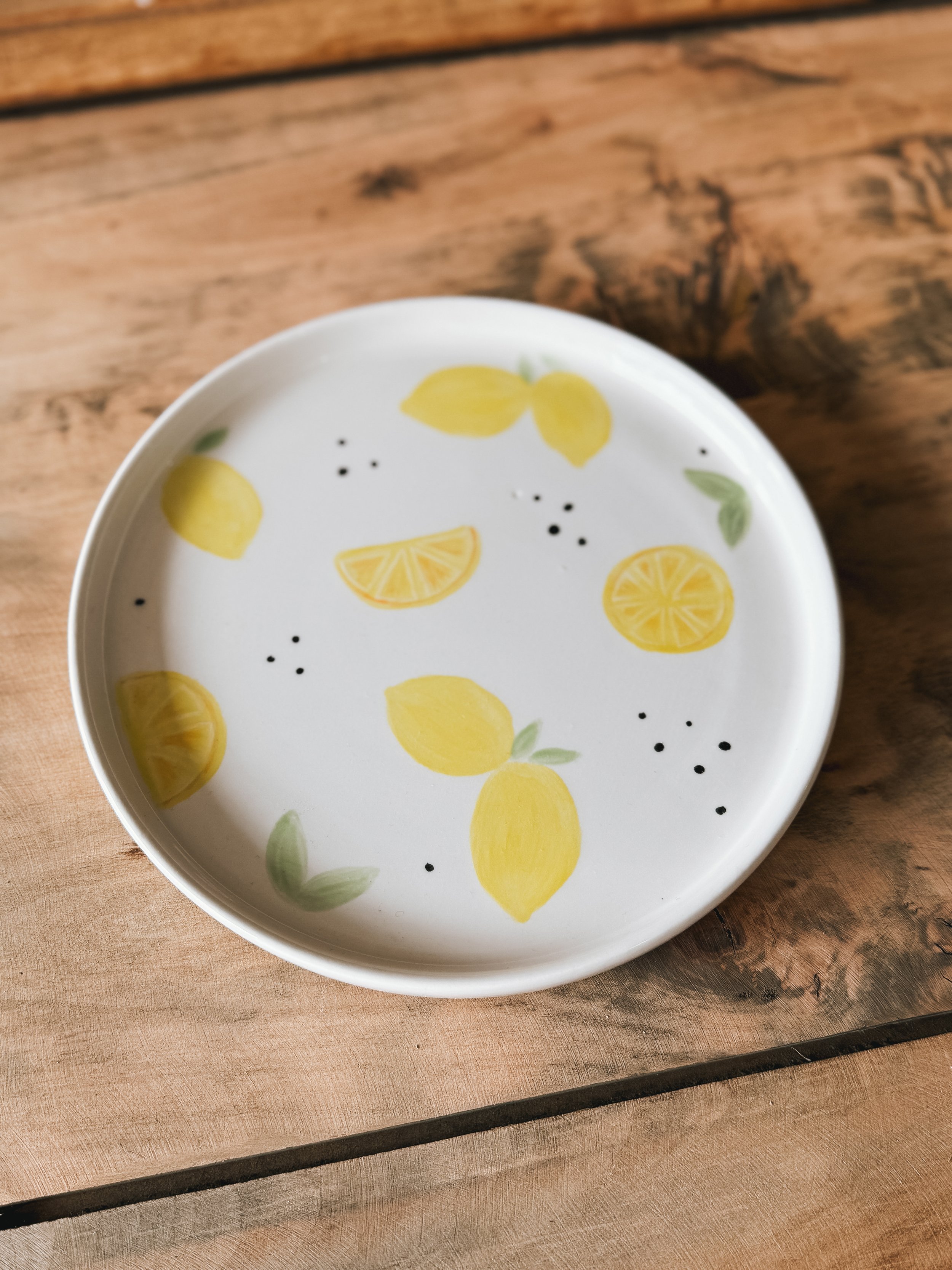 Petite assiette illustrée avec des citrons et quelques feuilles, réalisée lors d'une séance de peinture sur céramique.
