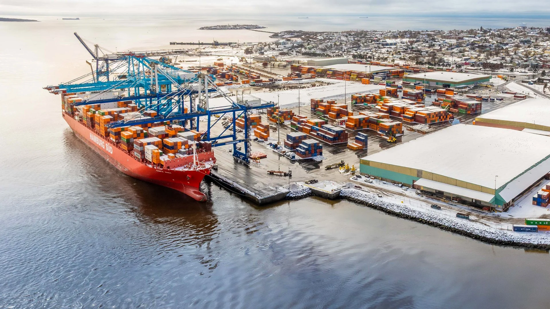 Aerial view of Port Saint John’s West Side container terminal with a docked ship and stacked containers.