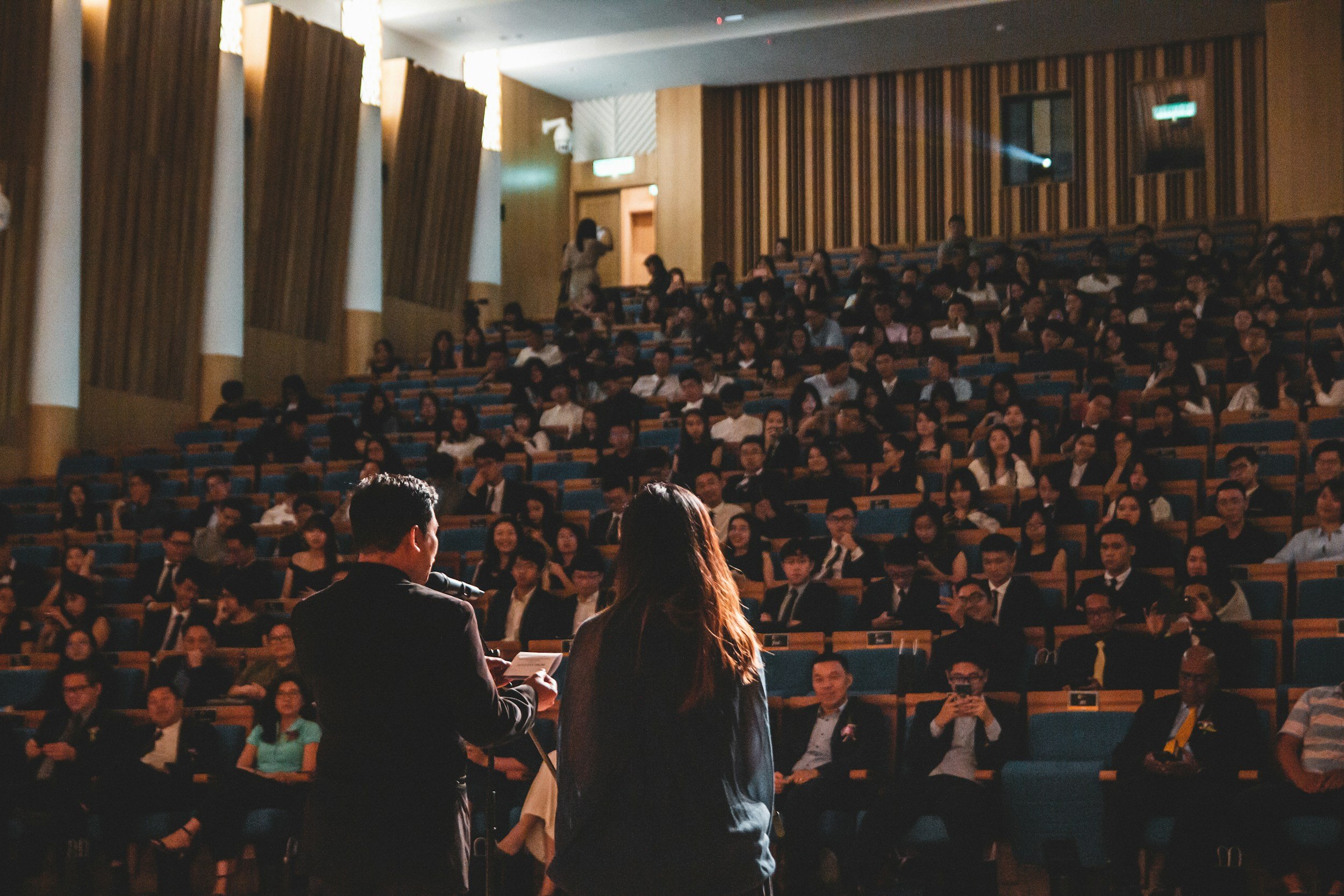 Large auditorium with male and female speakers onstage