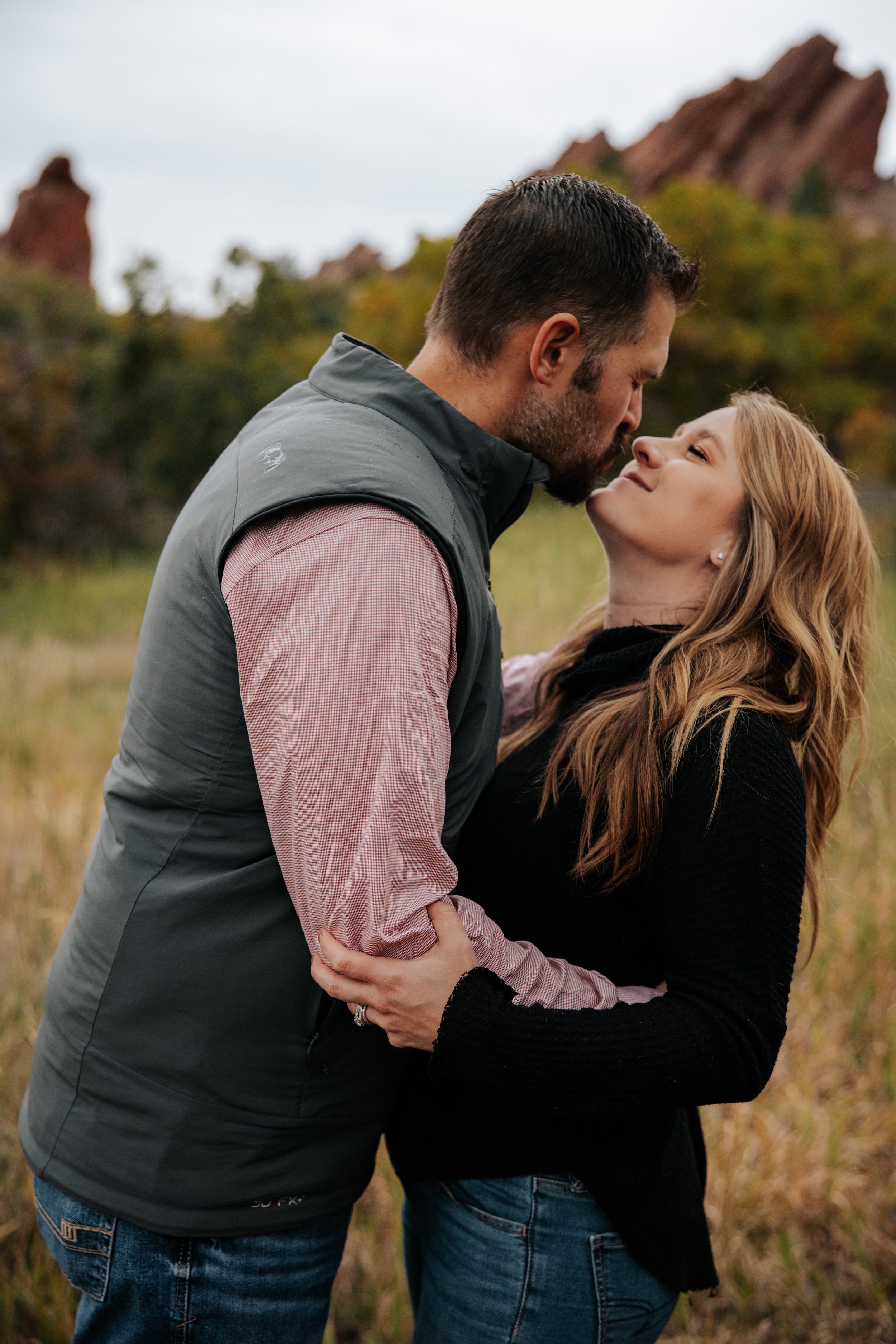 A couple embracing outdoors with mountains in the background.