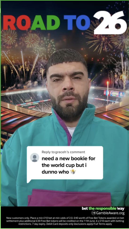 A man with dark hair and beard wearing a teal jacket with purple accents in front of a stadium with fireworks, with the text 'Road to 26' and a comment about needing a new bookie for the World Cup.