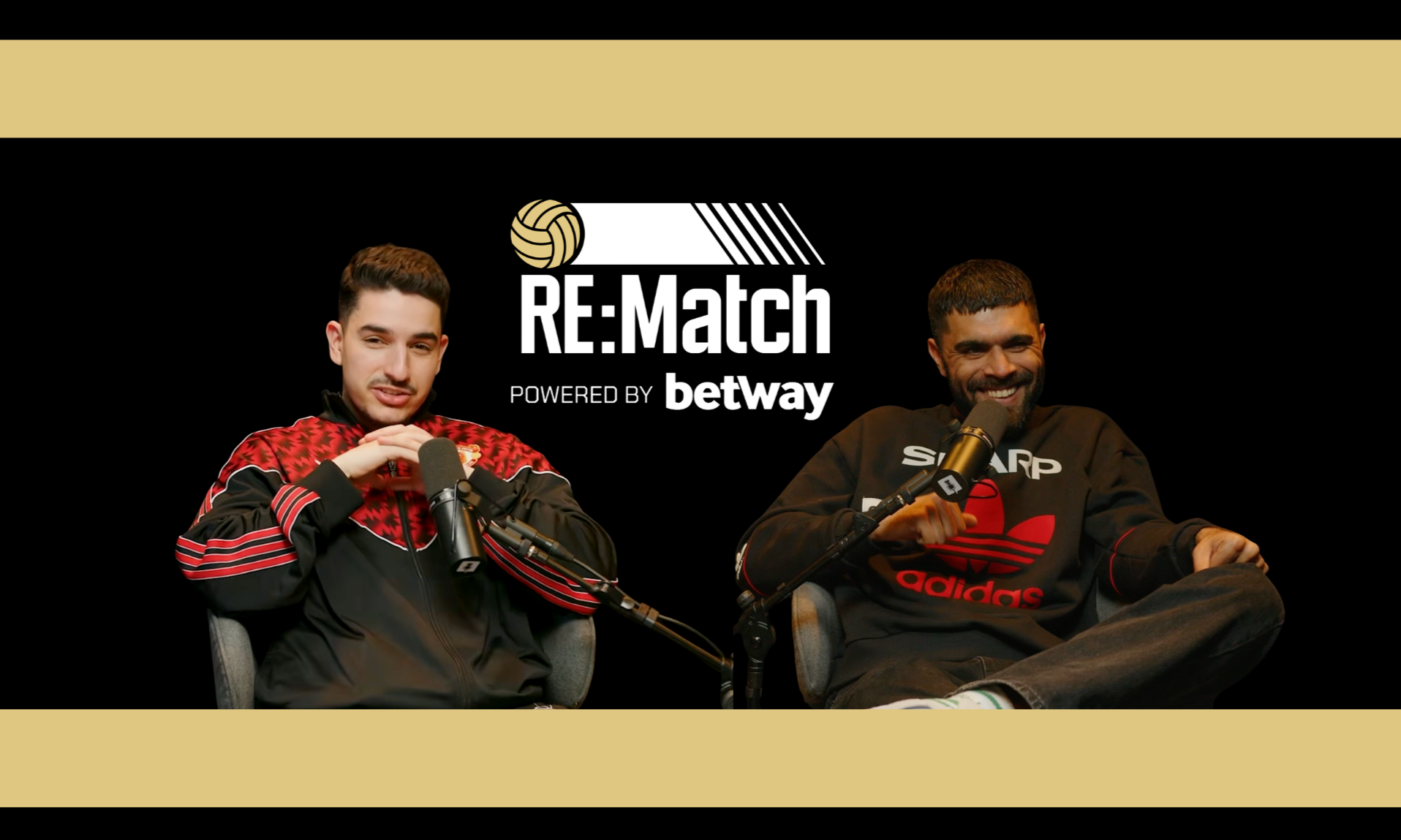 Two men seated at microphones during a podcast or interview, with a logo in the background that reads 'RE:Match powered by betway'; one man is wearing a red and black sports jacket, the other is wearing a black Adidas sweatshirt.