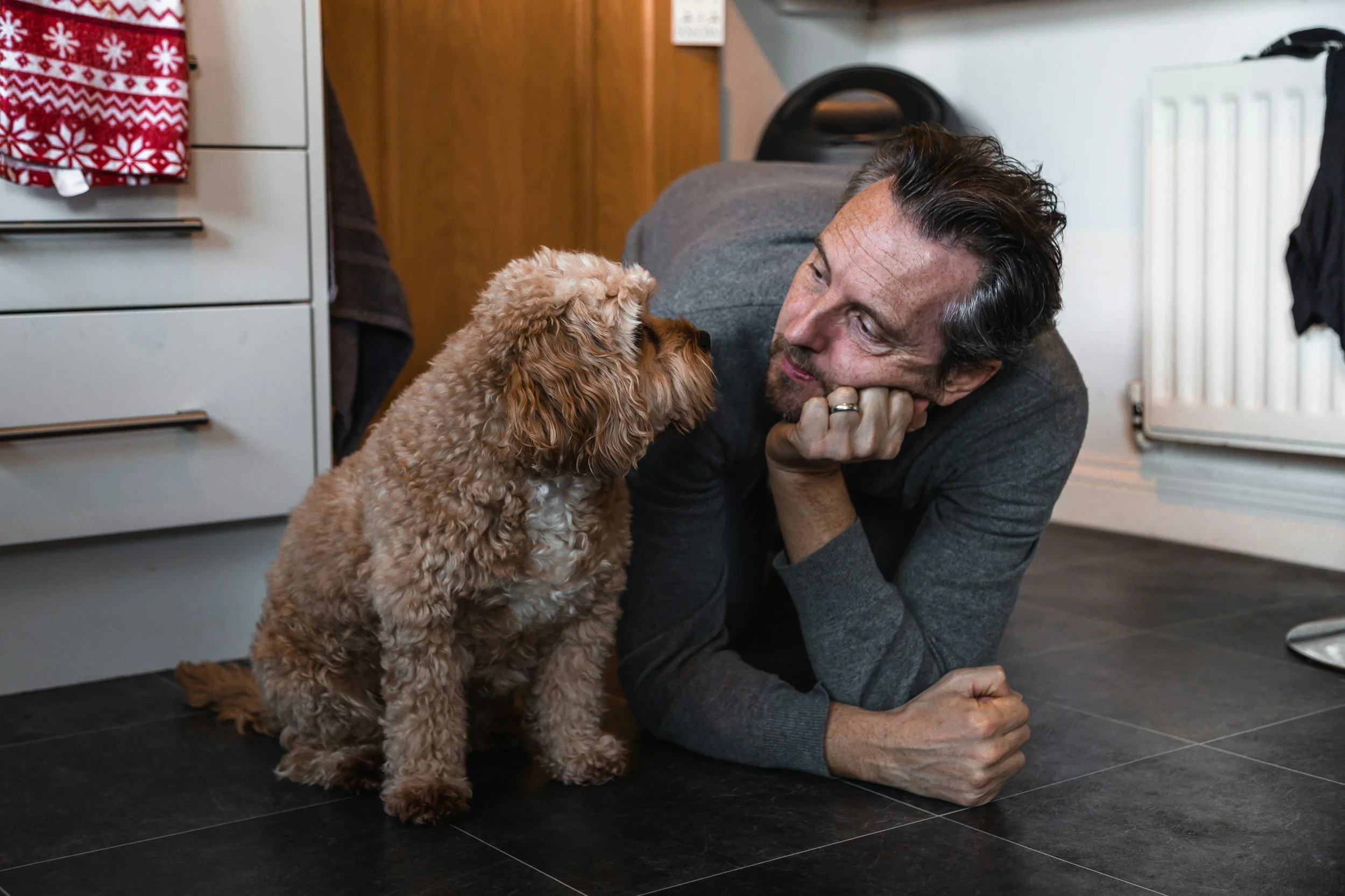 Man and older poodle-mix-type dog sitting nose-to-nose, looking directly at one another.