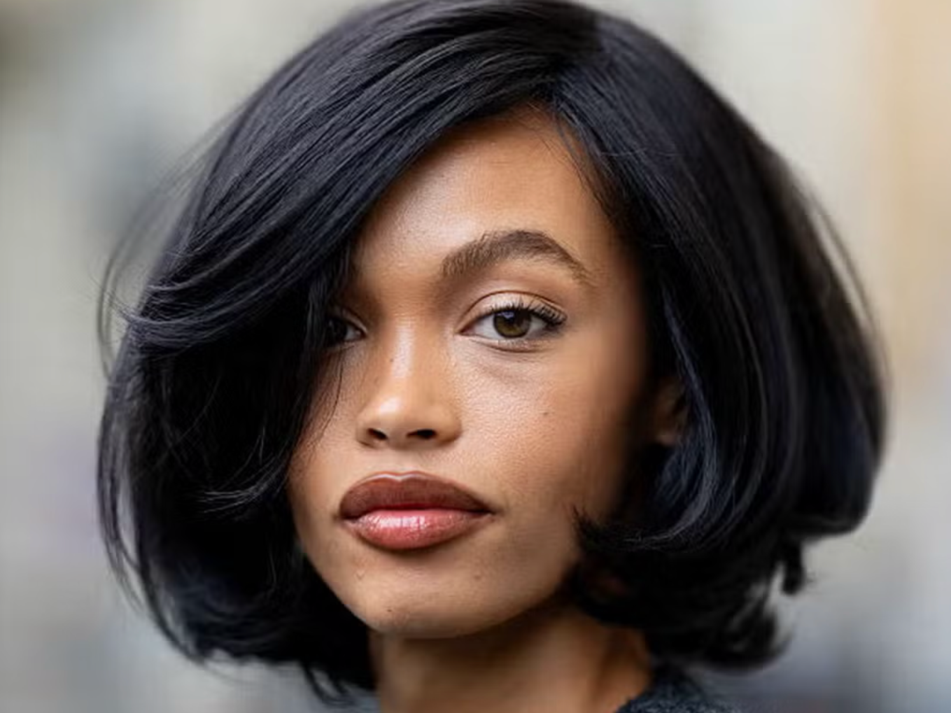 Short swishy dark hair bob image on woman wearing a grey cardigan