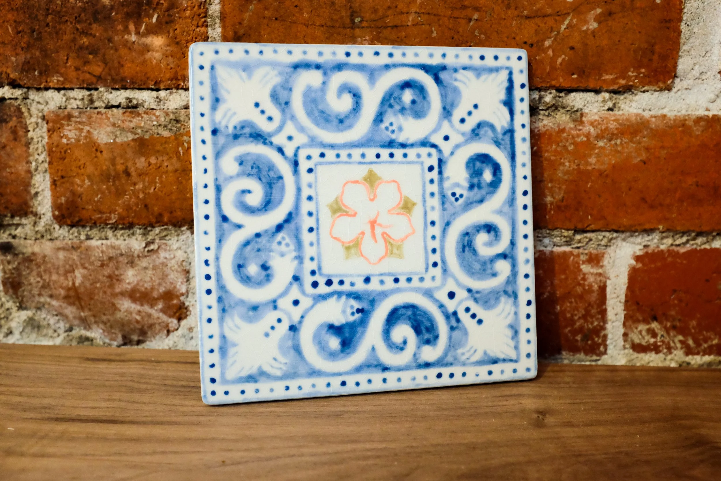 Decorative azulejo tile with a peach blossom in the center, and spanish ornamental features bordering it