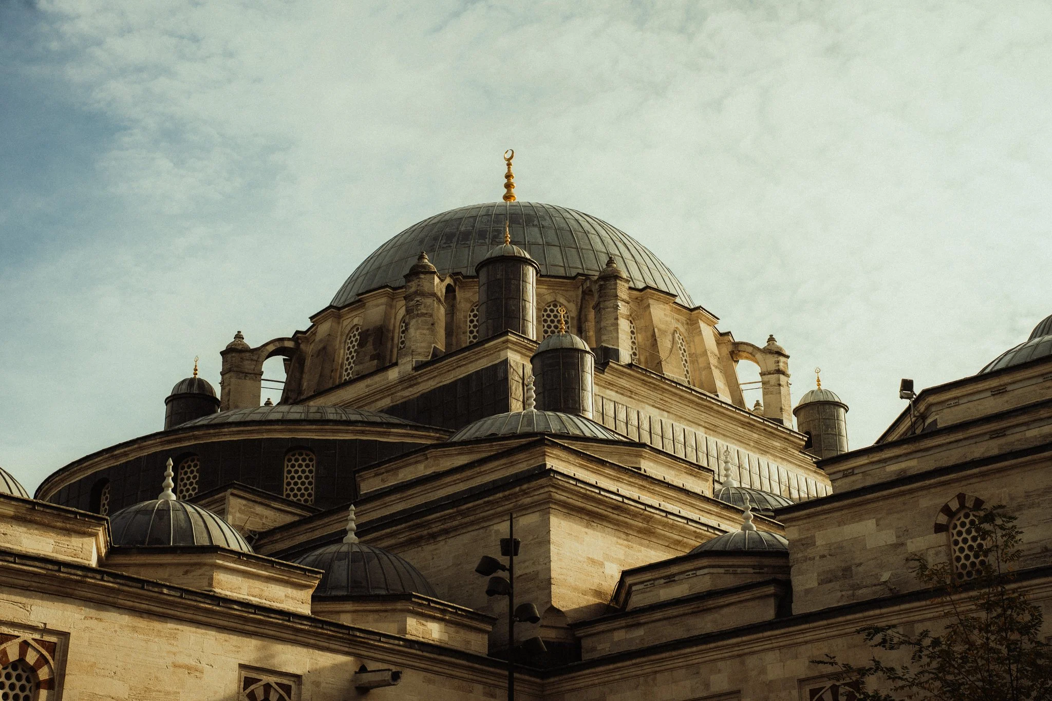 A mosque in Istanbul with multiple domes and minarets under a cloudy sky.
