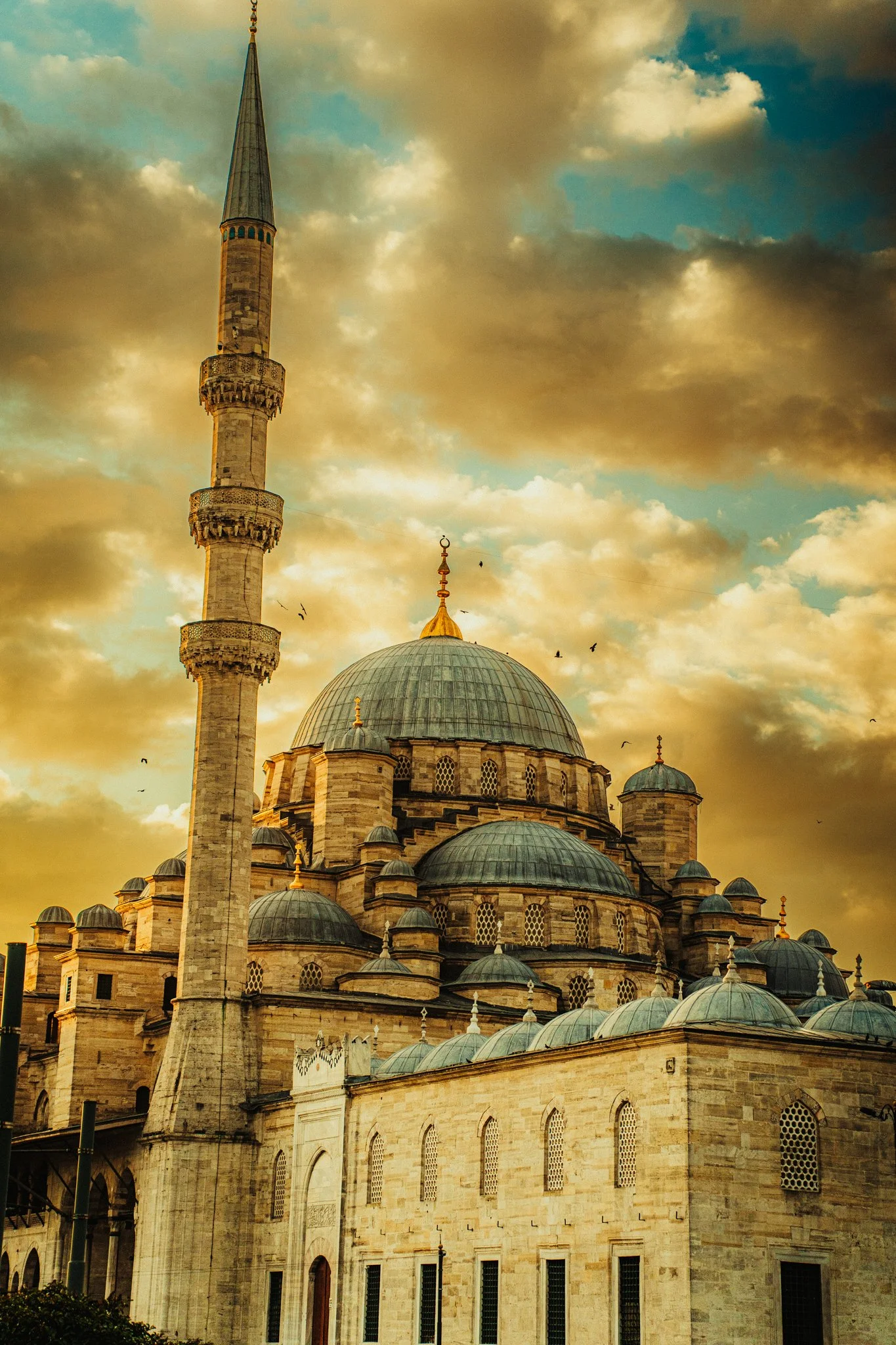 The Blue mosque with multiple domes and a tall minaret during golden hour with a cloudy sky in the background.