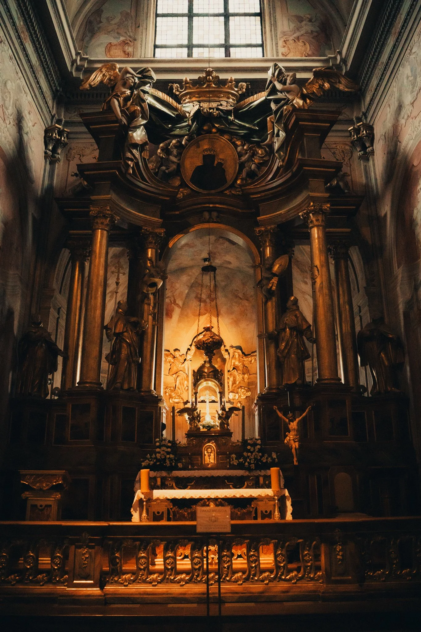 Inside a richly decorated Catholic church altar with gold accents, statues, and religious artifacts.